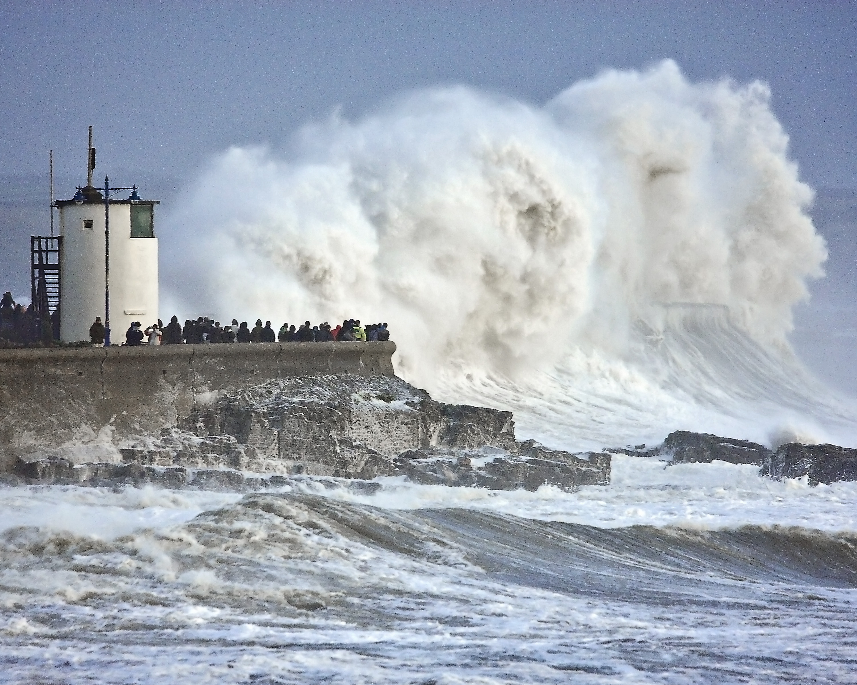 Waves smother Porthcawl breakwater and lighthouse