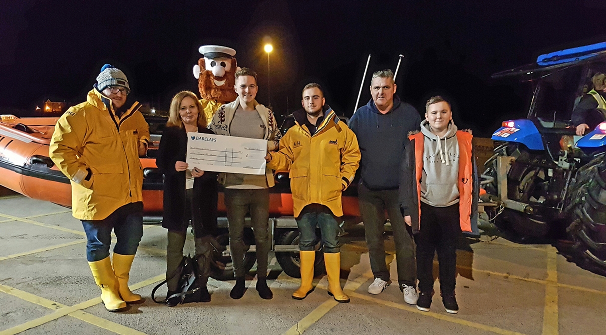 Barmouth RNLI volunteer crew members Anthony Schorah, Alex Hill and RNLI mascot Stormy Stan receiving the cheque from the Bowater family.