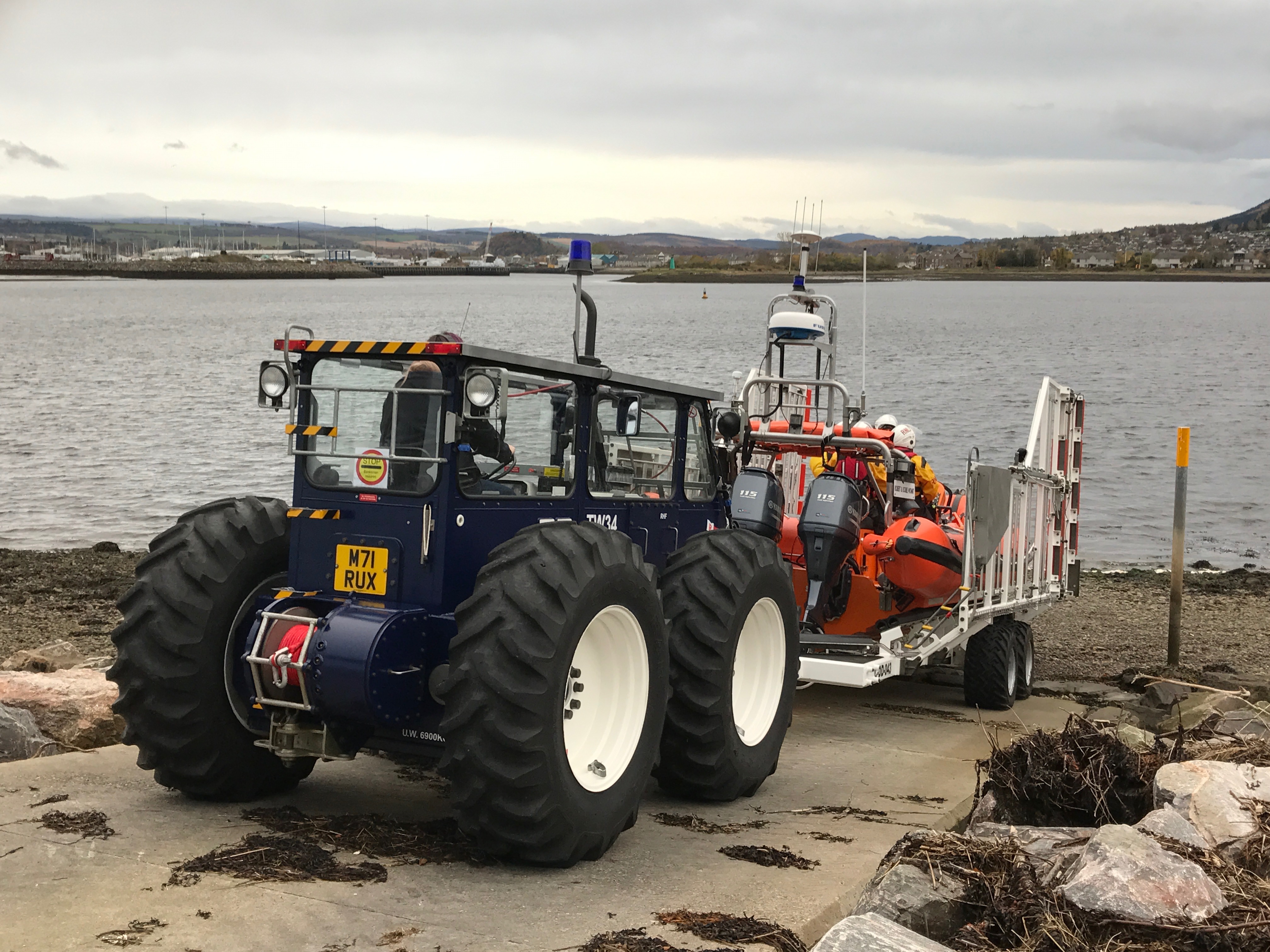 Lifeboat on trailer being driven by tractor down slipway to the water