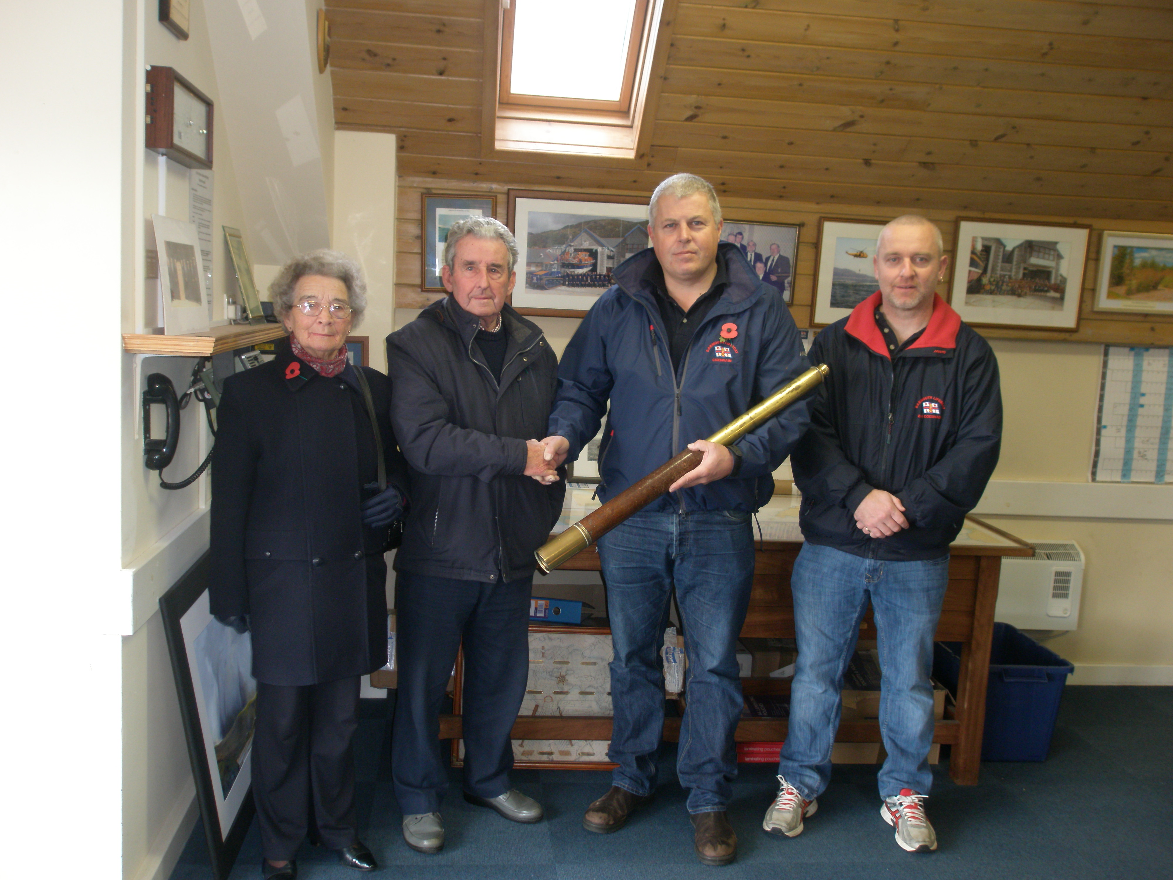 Sybil Jones and Robert Wyn Jones, ex-crew member and descendant of first Barmouth RNLI Coxswain Humphrey Jones, presents the telescope to current Coxswain Peter Davies and Second Coxswain Rob Williams