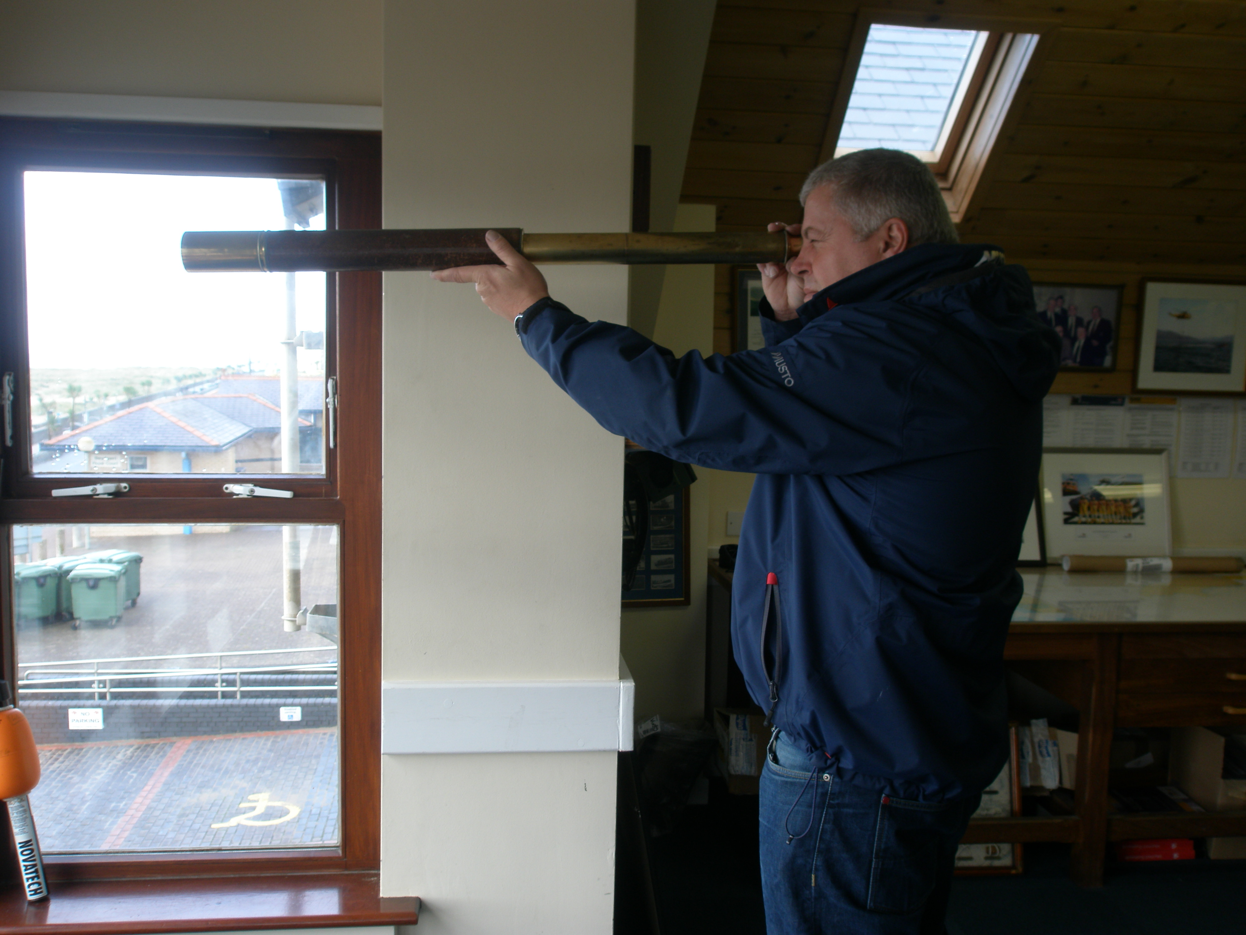 Barmouth RNLI Coxswain Pete Davies looking out to sea with the antique telescope