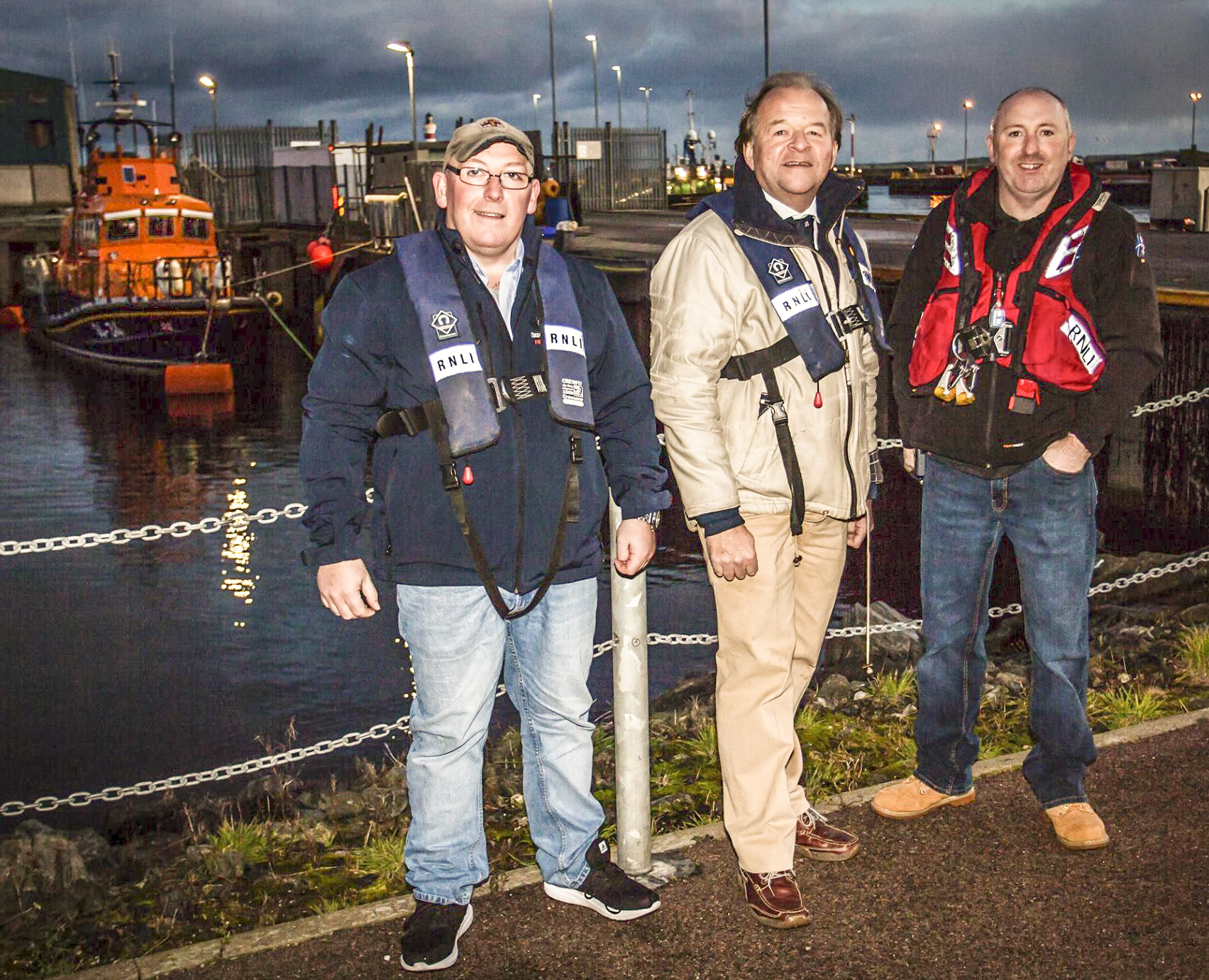 New RNLI Chairman Stuart Popham, Coxswain Vic Sutherland and new Lifeboat Operations Manager Hamish Partridge outside the Fraserburgh RNLI Station and the Lifeboat in the background.