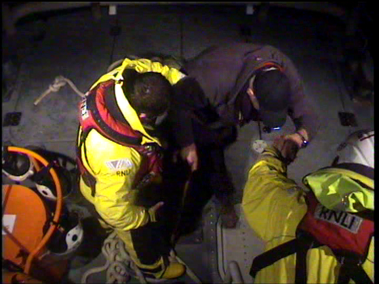 Tenby RNLI volunteer crew assist a crewman from the stricken vessel