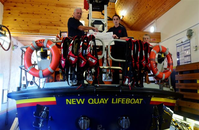 Daniel Williams aboard New Quay RNLI's Mersey class all weather lifeboat, the Frank and Lena Clifford of Stourbridge, handing over a cheque for £413 to Lifeboat Operations Manager, Roger Couch