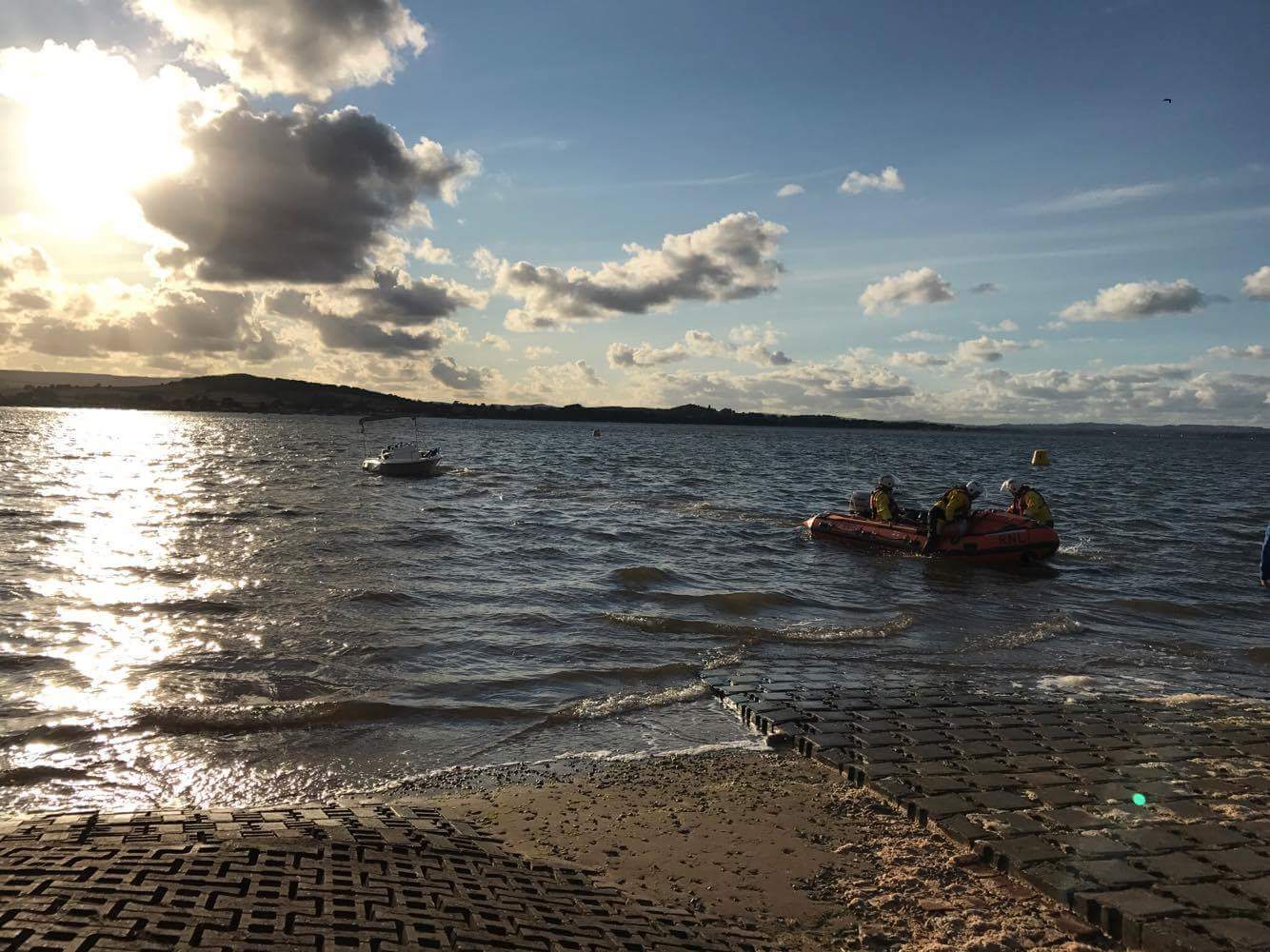 Crew on board inshore lifeboat George Bearman II tow the capsized boat out of the river Exe.
