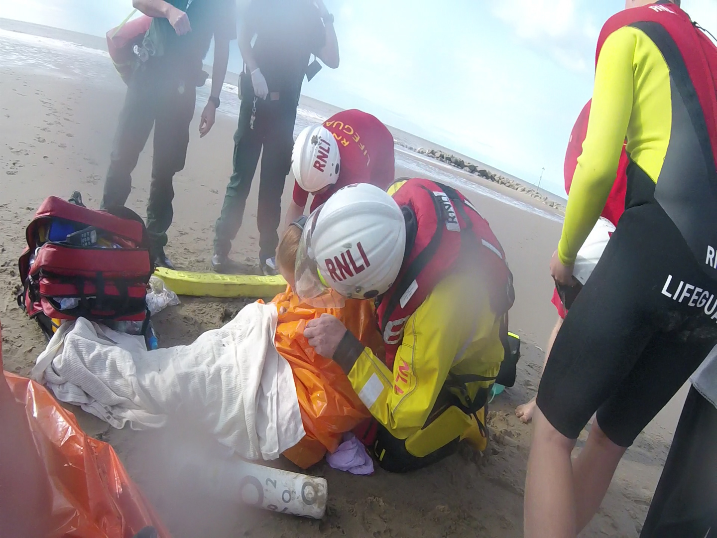 RNLI lifeguards and lifeboat crew provide casualty care as ambulance personnel arrive. Coastguard Helicopter circling