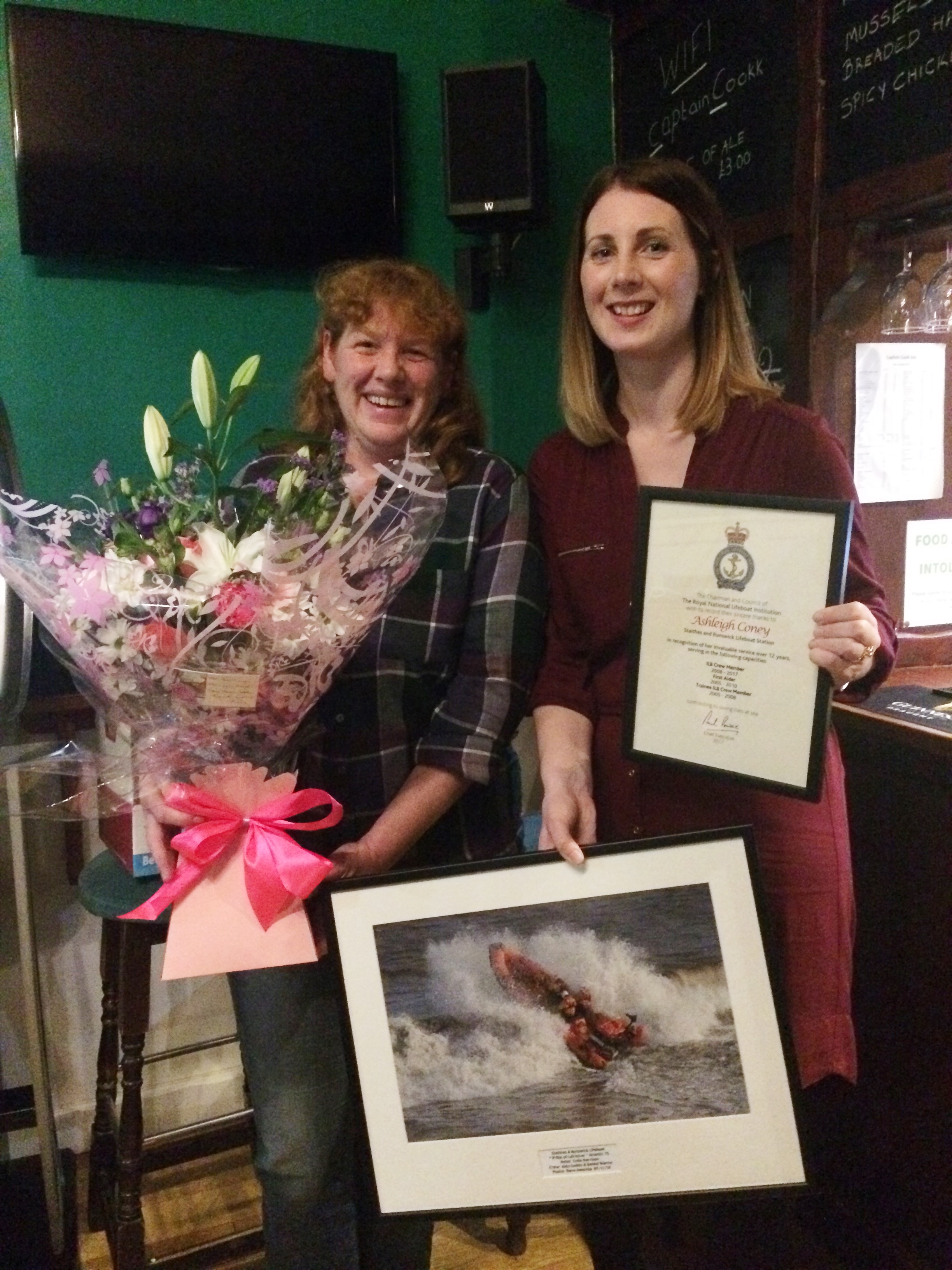Women crew members with flowers and framed awards