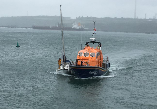 Angle RNLI's all weather Tamar Class lifeboat Mark Mason approaches Milford Docks with the rescued yacht in an alongside tow