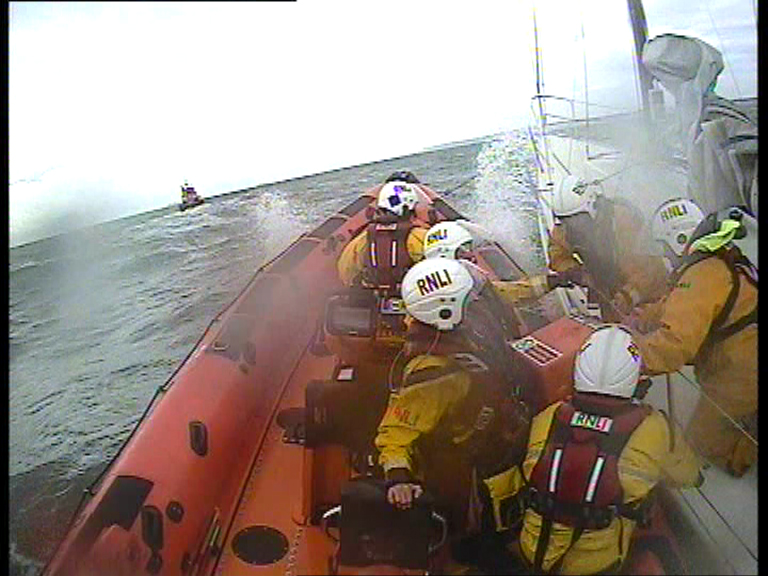 The crew of the Walmer Atlantic 85 pass the pump to Dover RNLI volunteers on board the yacht