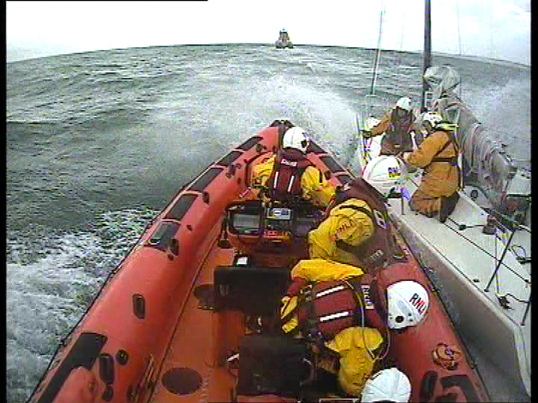 The Walmer lifeboat pulls alongside the yacht with the Dover lifeboat on the horizon