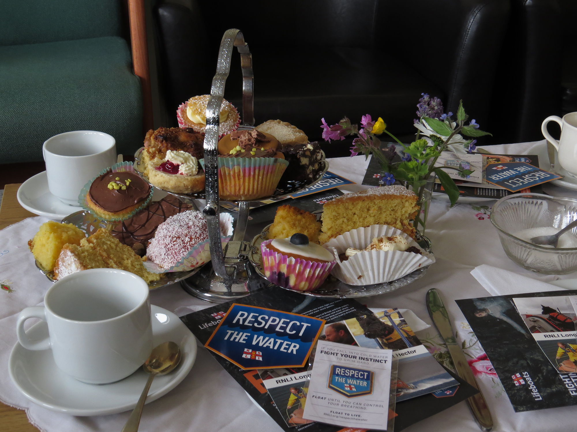 Tables set for cruise liner passengers with fancy home baked cakes and Respect the Water promotional items.