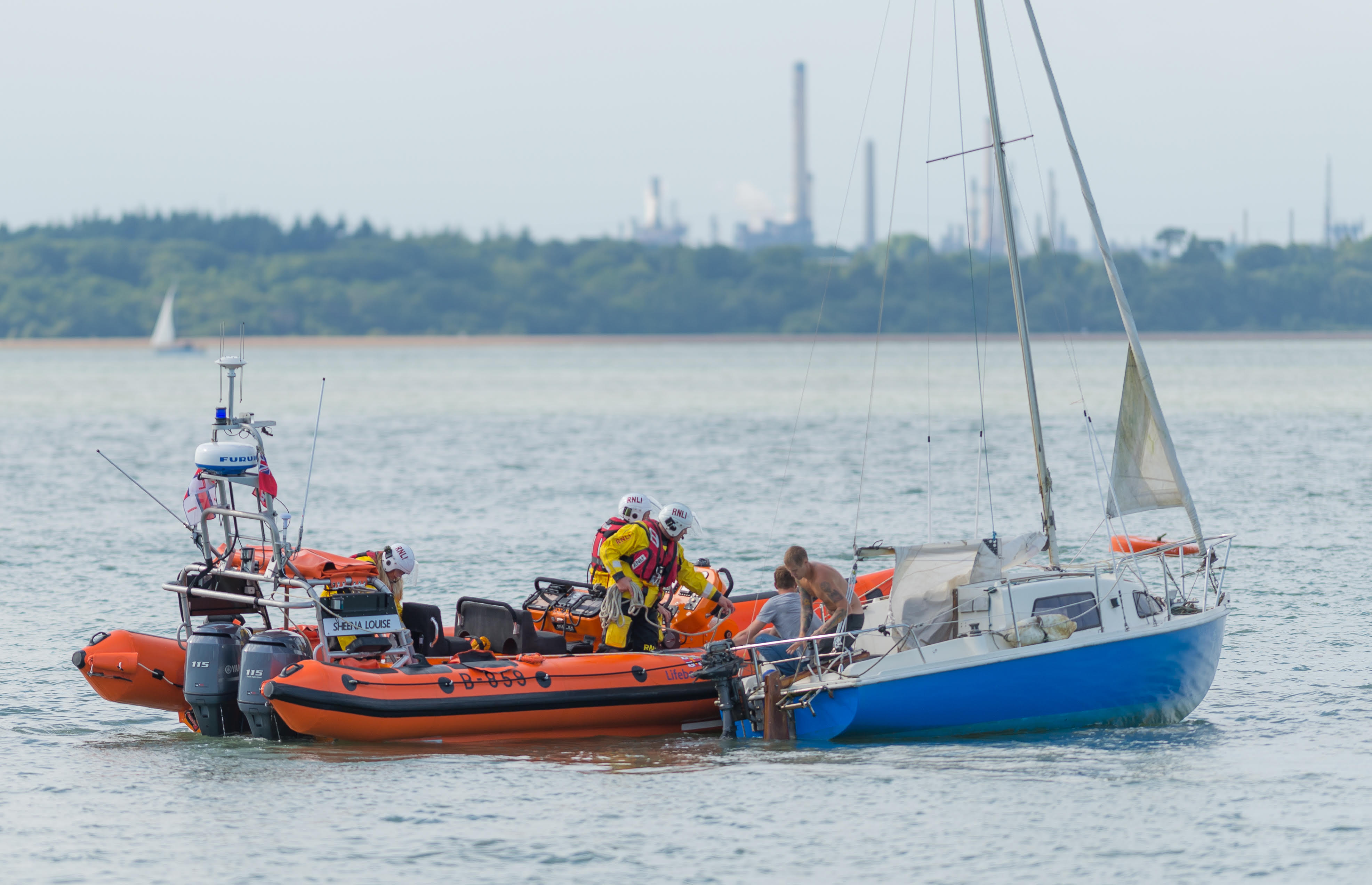 The yacht is being prepared for towing by the lifeboat.