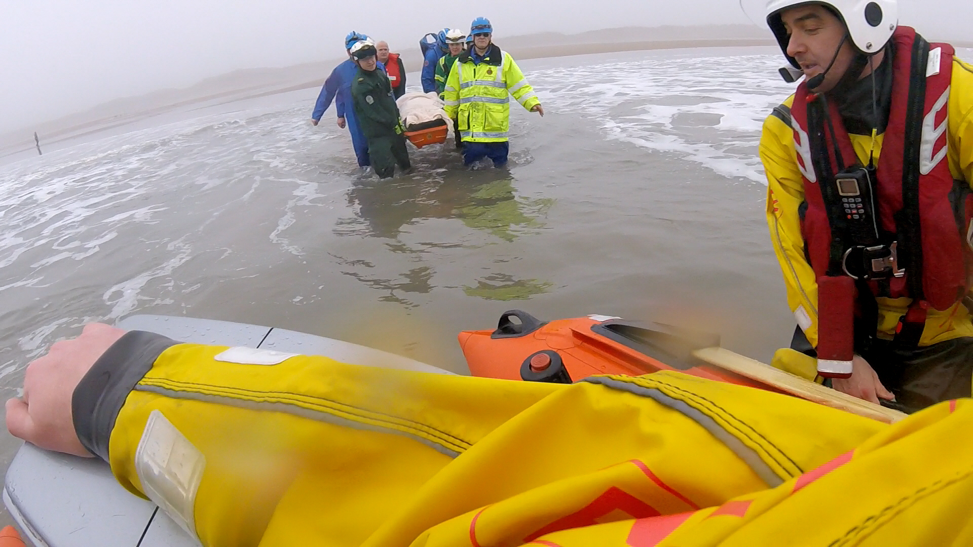 Multi agency personnel carry strechered casualty from the beach to the waiting D Class