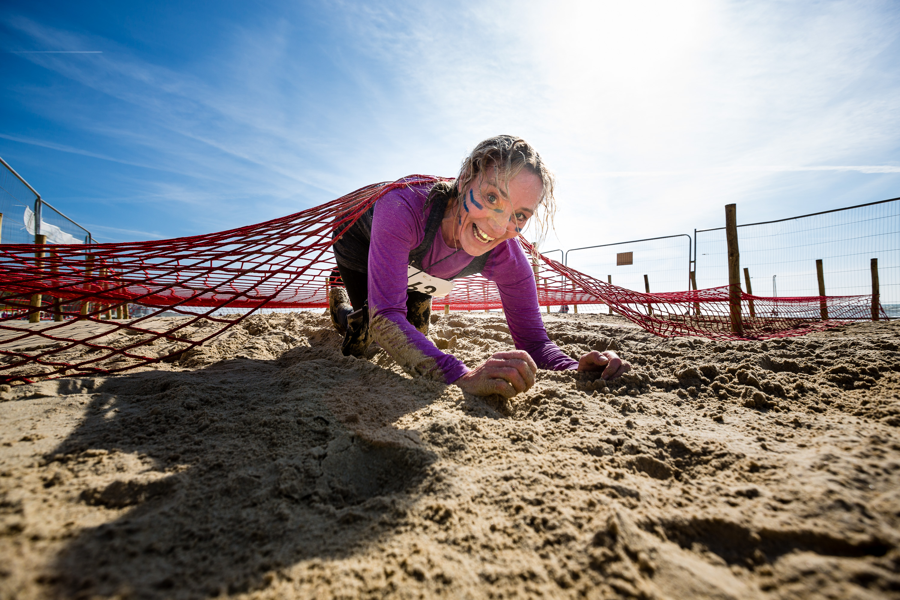 Participant crawls under The Scrambler’s cargo net.