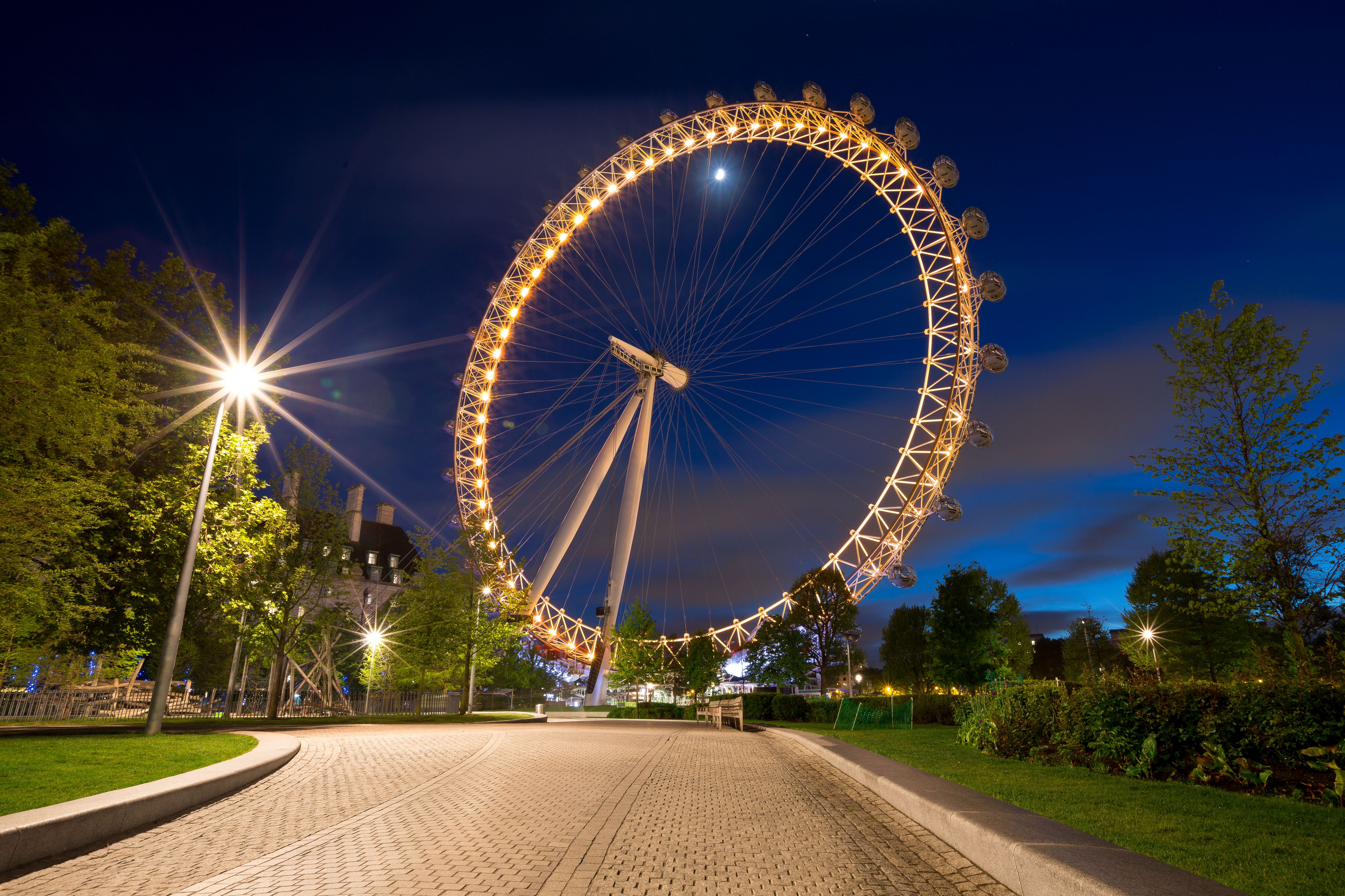 The Coca-Cola London Eye shines yellow, with Jubilee Gardens park in the foreground