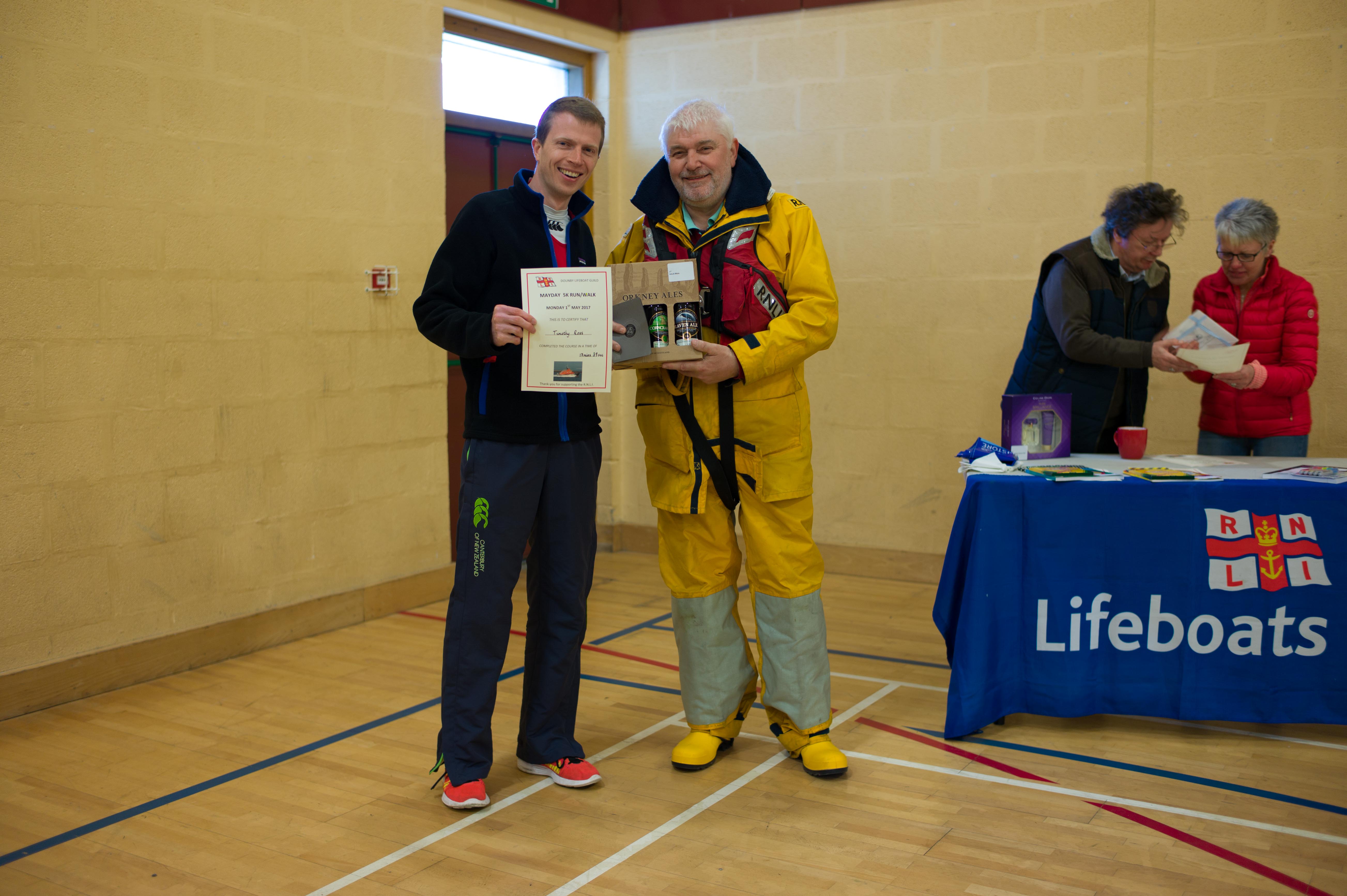 Photo shows Fred Breck standing alongside Tim Ross handing over beer and a certificate
