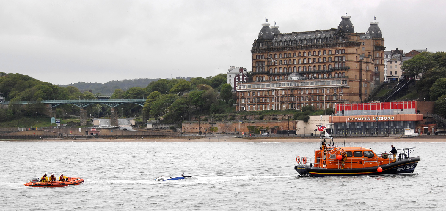The wrecked Don’t Panic is towed to a pier