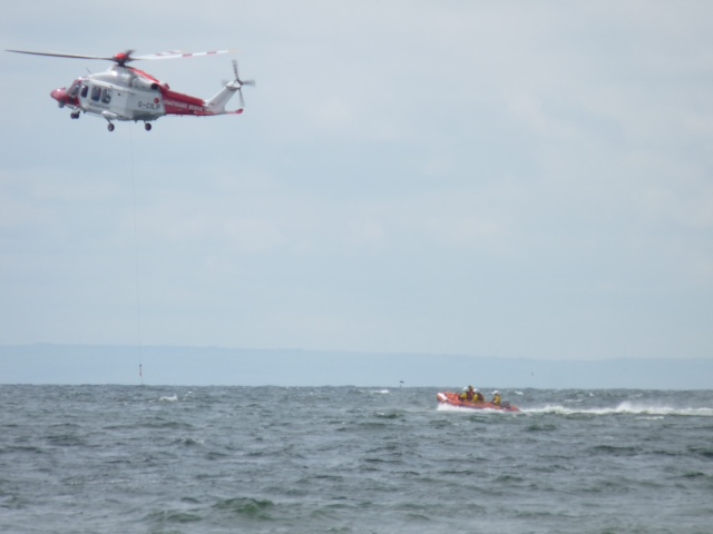 The Coastguard helicopter preparing to winch up a lifeboat crew volunteer