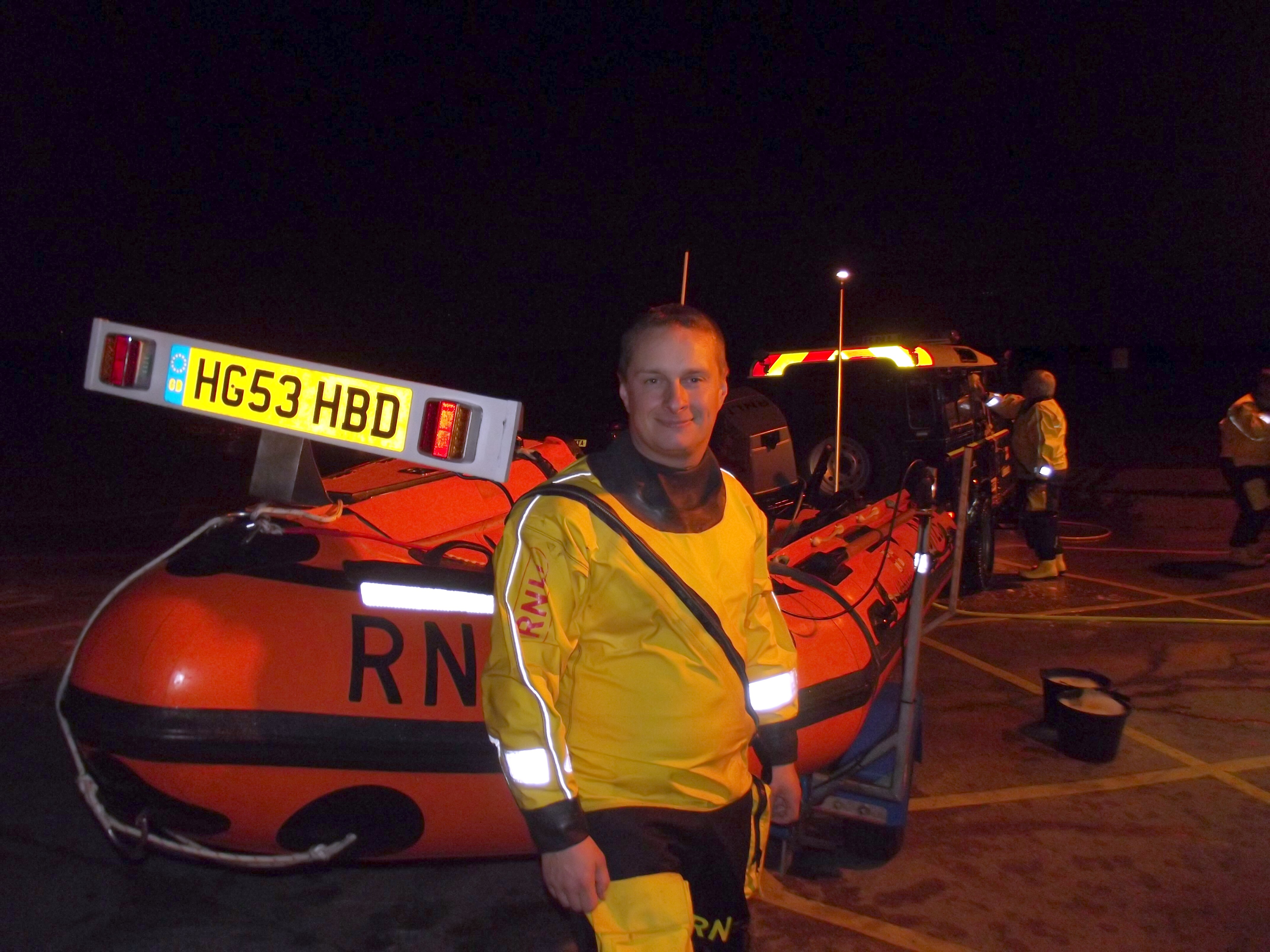 A lifeboat crew member stands in front of an ILB and Land Rover