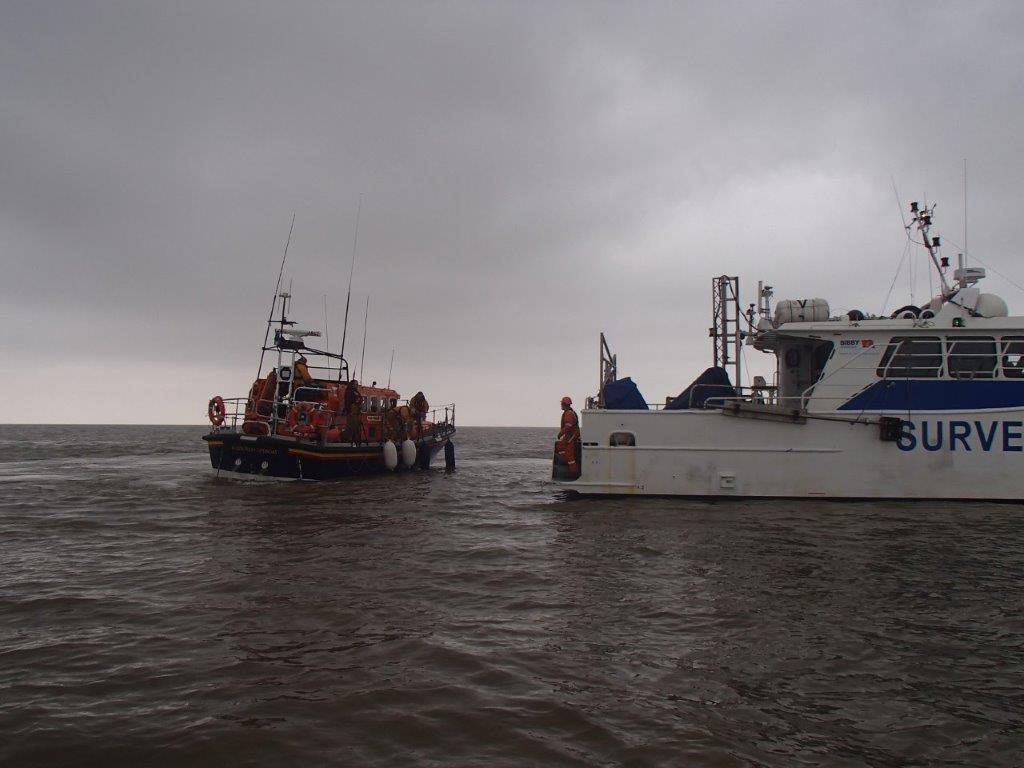 Aldeburgh All-Weather Lifeboat alongside the survey ship, with the casualty onboard.