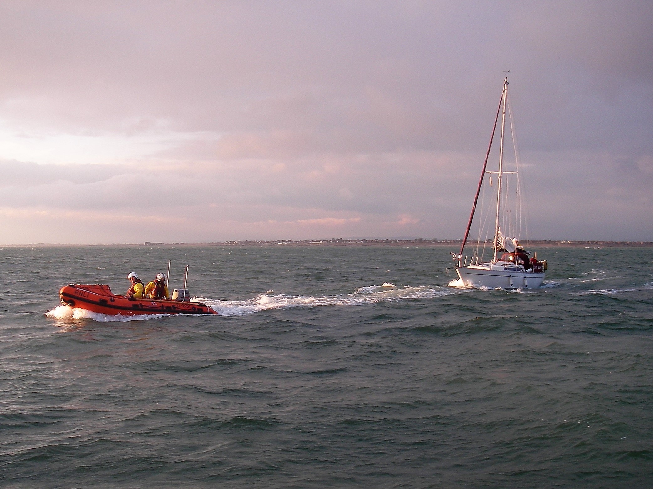 Inshore lifeboat towing the casualty vessel towards the all-weather lifeboat