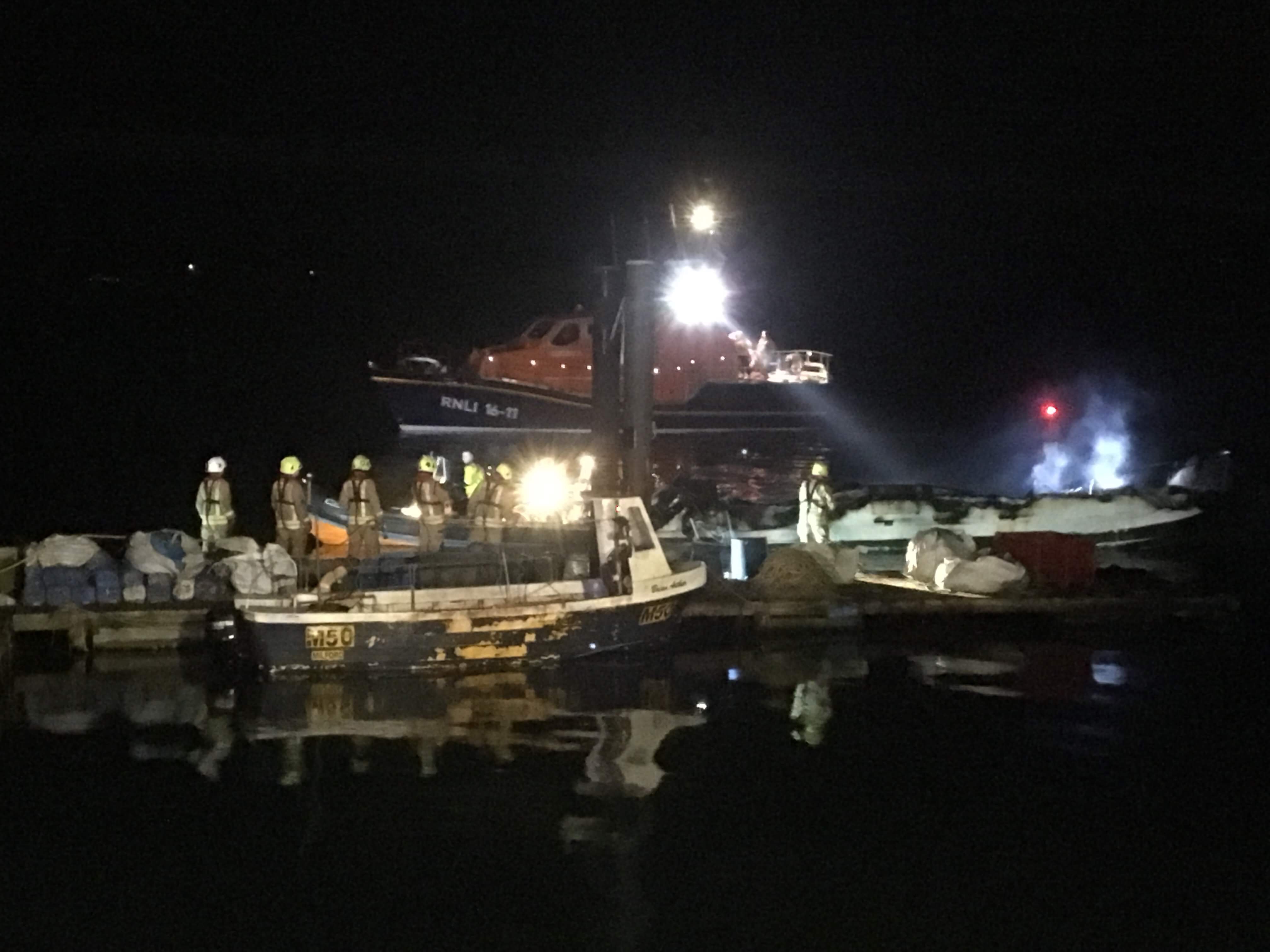 The scene at the pontoon at Neyland is illuminated by Angle RNLI’s all weather lifeboat after the Fire Service rescue boat had towed in the fishing vessel.