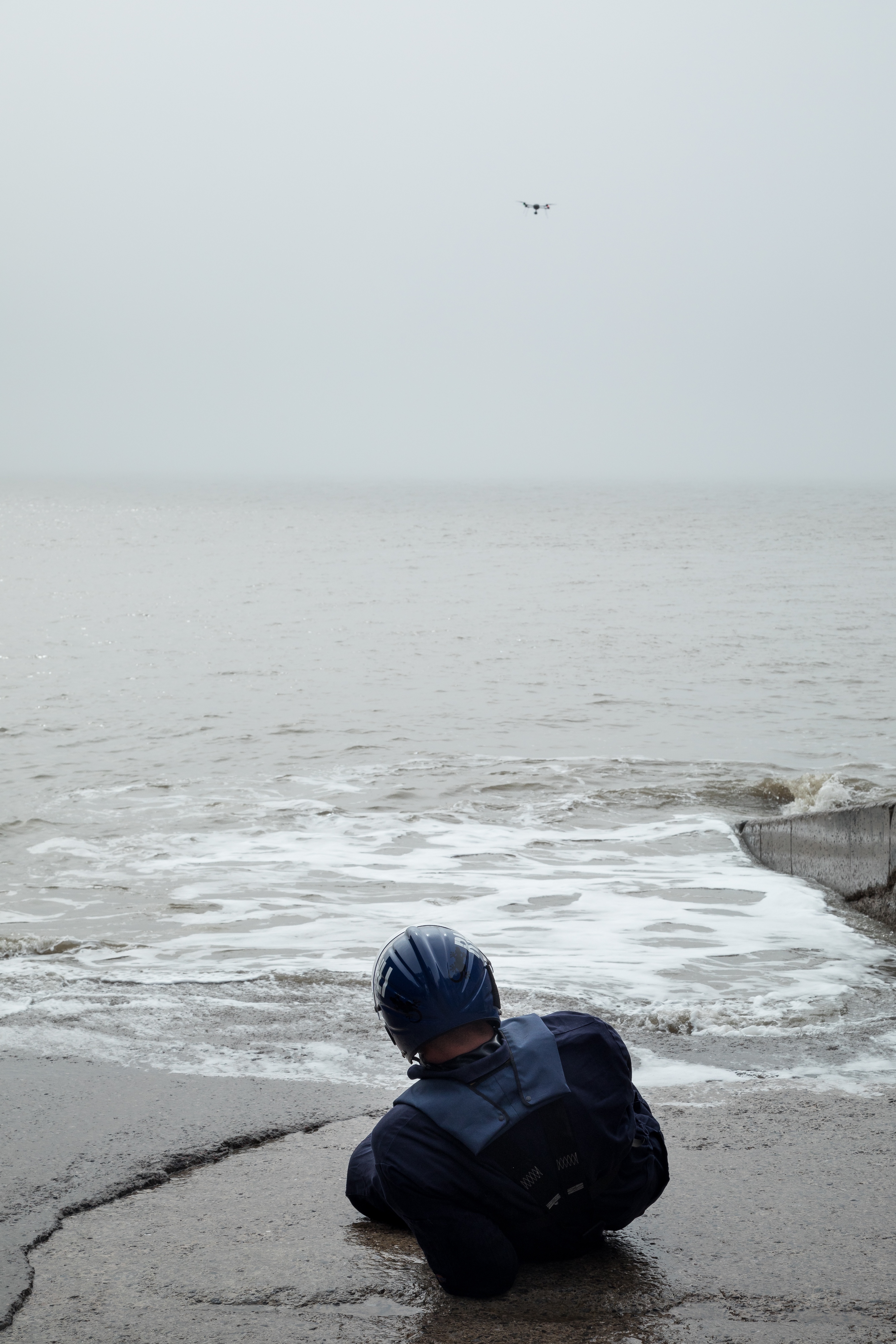 A drpne flies in the sky while a mock casualty lies on the shoreline
