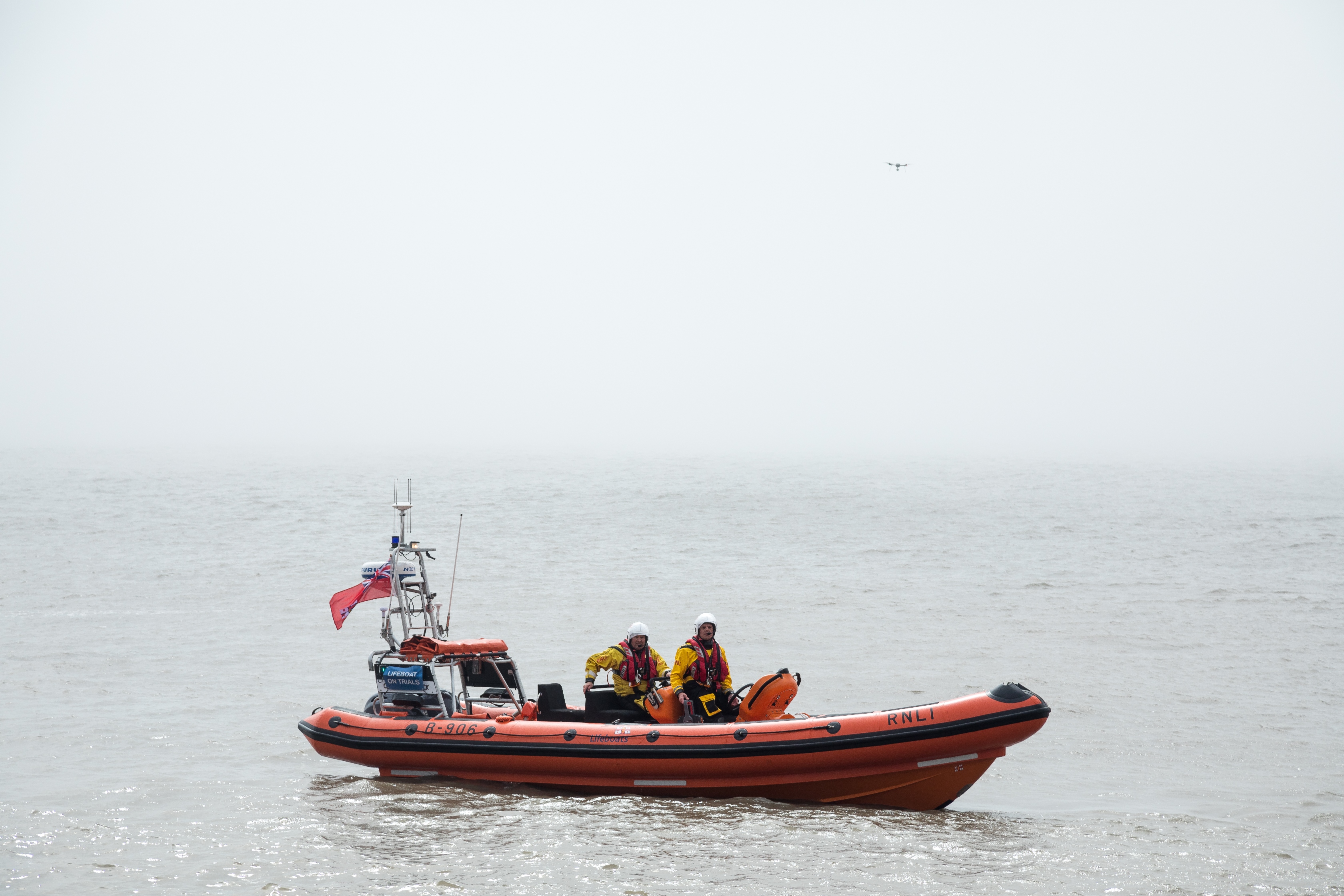 An RNLI inshore lifeboat on the sea with a drone flying above the vessel