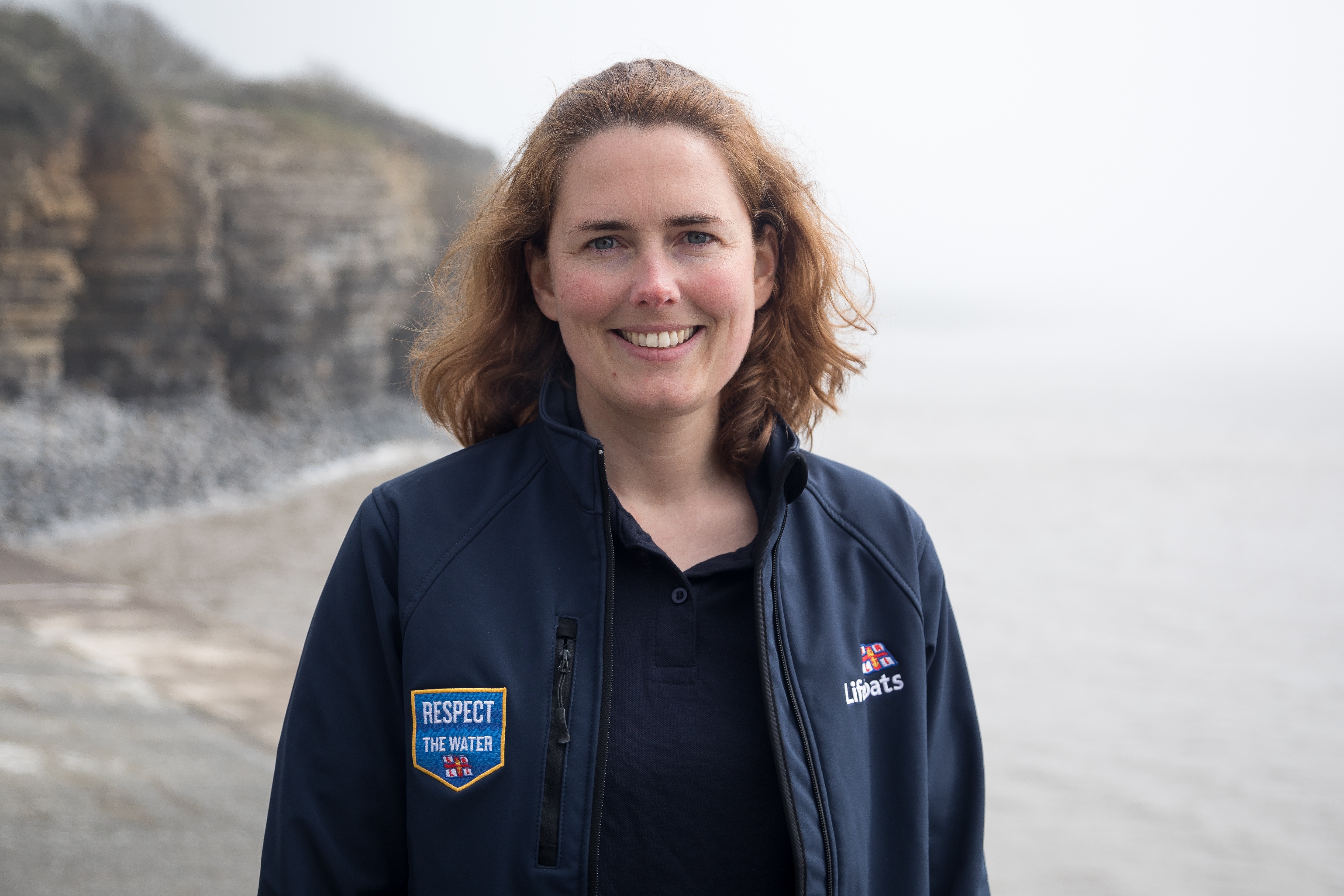 RNLI Innovation Scout Hannah Nobbs smiling for the camera with coastline in the background