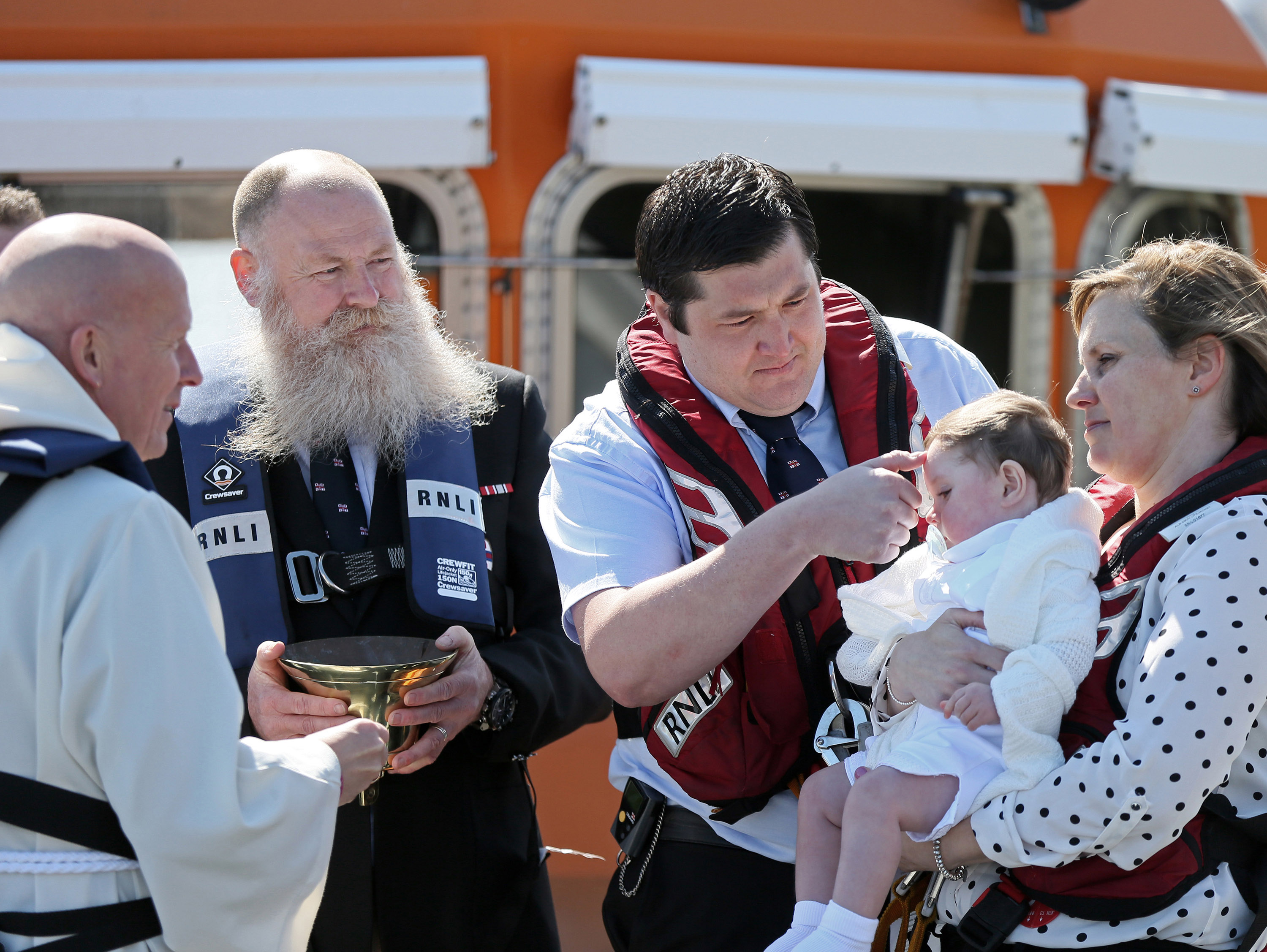 29 April 2018 RNLI Lifeboat christening - Harry Thomas Michael Brown is christened on board Tynemouth RNLI station's Severn class all weather lifeboat Spirit of Northumberland by Revd Canon Glyn Evans in front of proud parents Laura and Michael, the Godparents, family and friends, and Michael's fellow RNLI lifeboat crewmembers. Please credit Adrian Don/RNLI