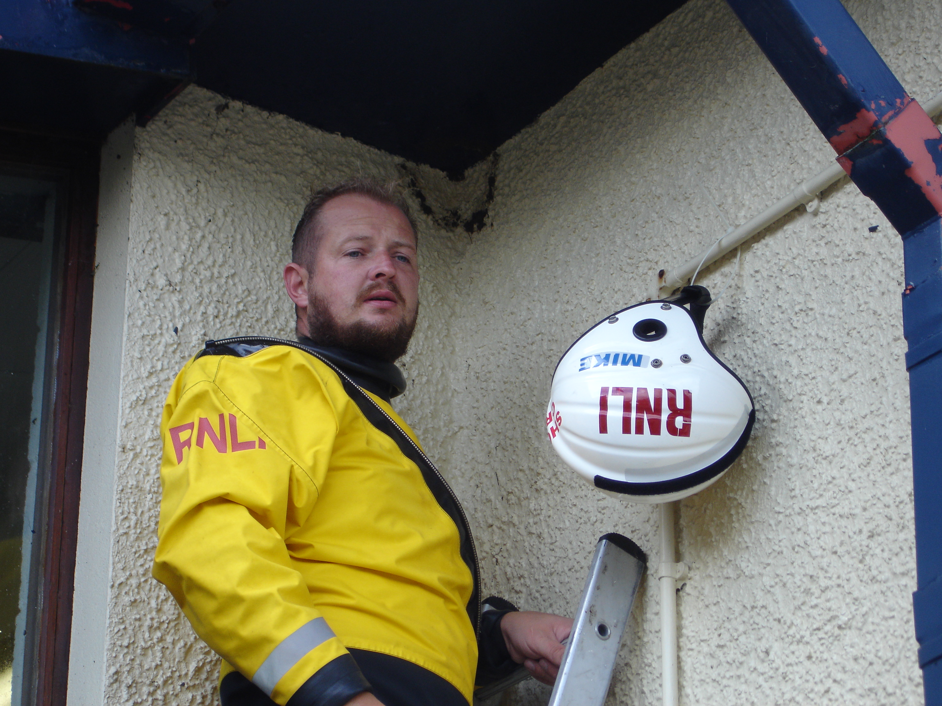 Crew member Gareth Owen attaching his helmet to the RNLI station wall