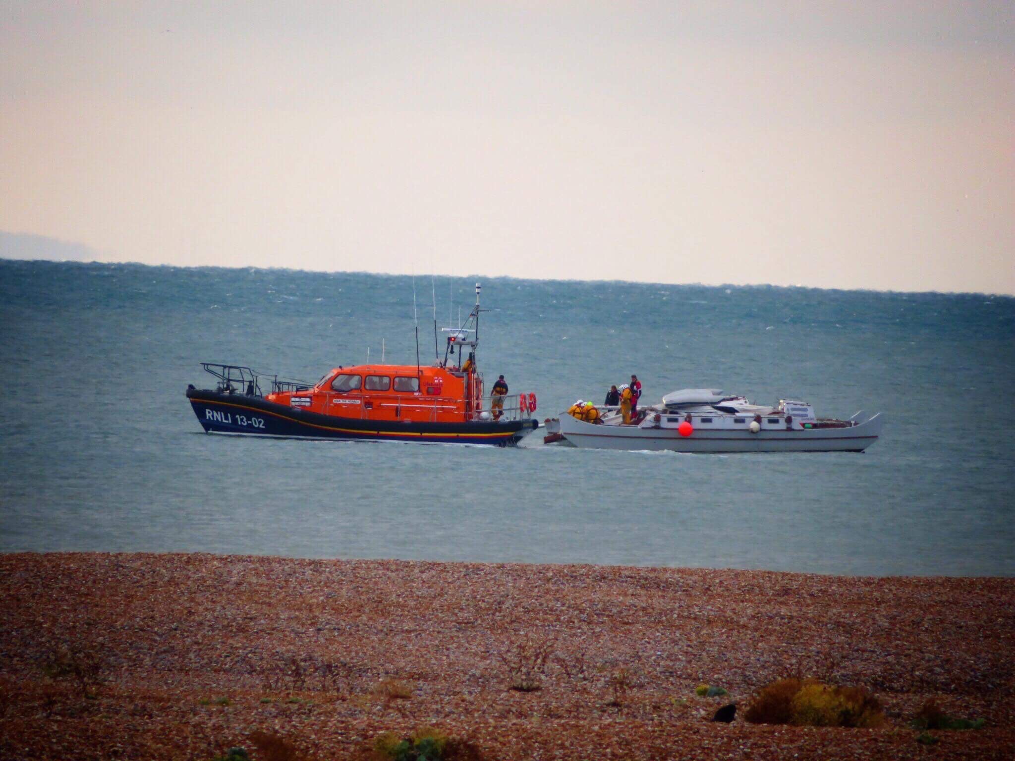 Photograph taken from the Dungeness beach of RNLI lifeboat safely securing stricken vessel