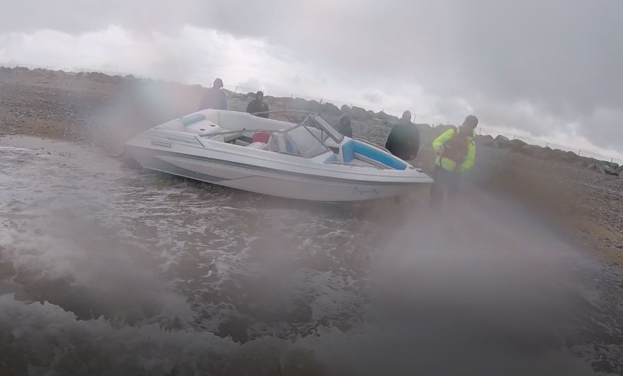 Vessel aground on beach with occupants and coastguards, prior to re-floating.