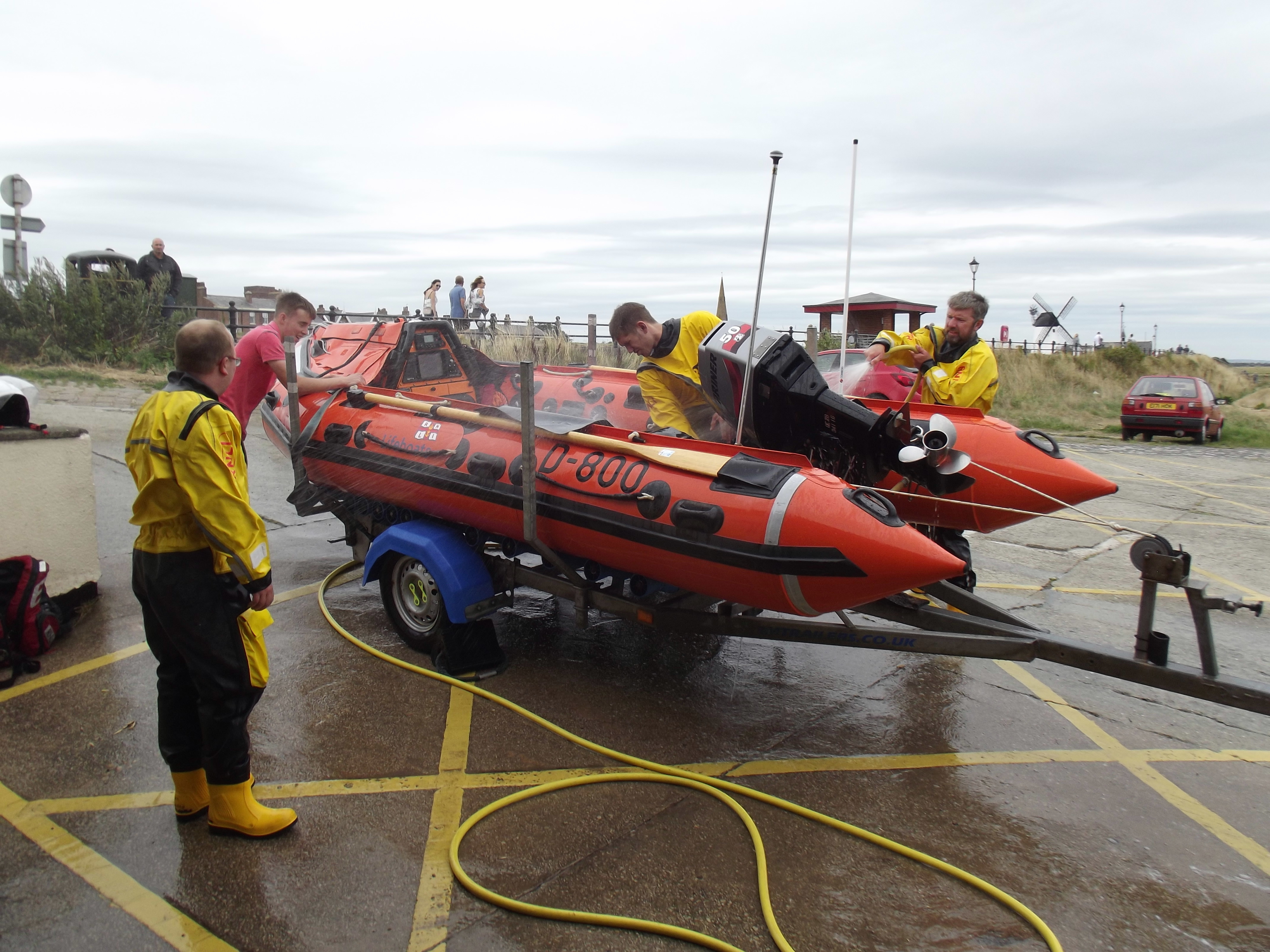 A group of lifeboat crew members surround an inshore lifeboat to clean and check her over.