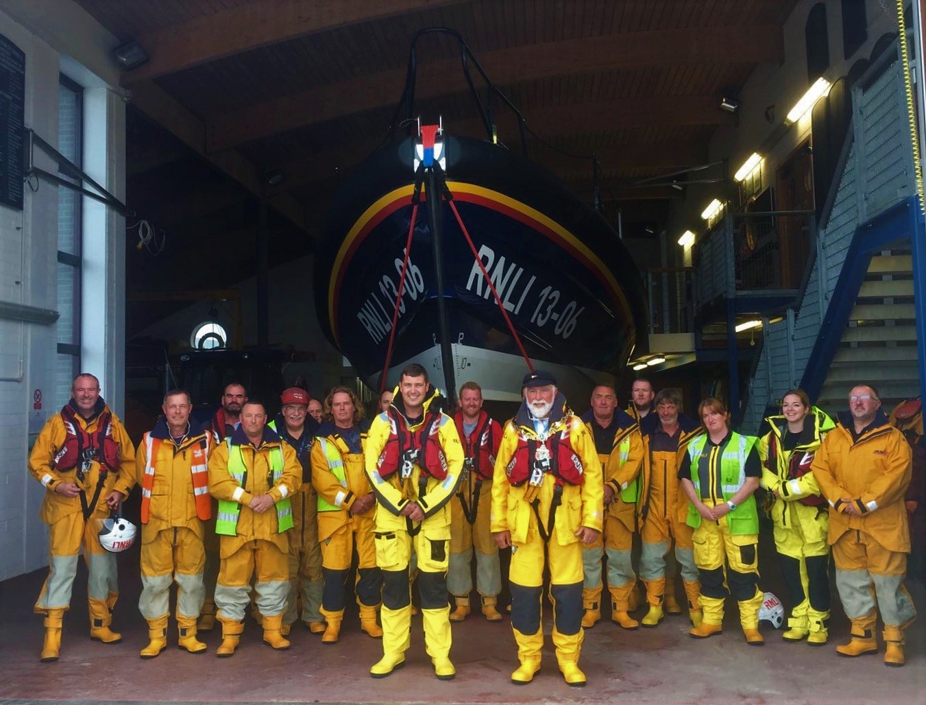 Councillor Geoffrey Watt, dressed in yellow RNLI all-weather gear and wearing his civic chain of office, stands with the Hoylake Lifeboat crew in front of the Shannon class lifeboat