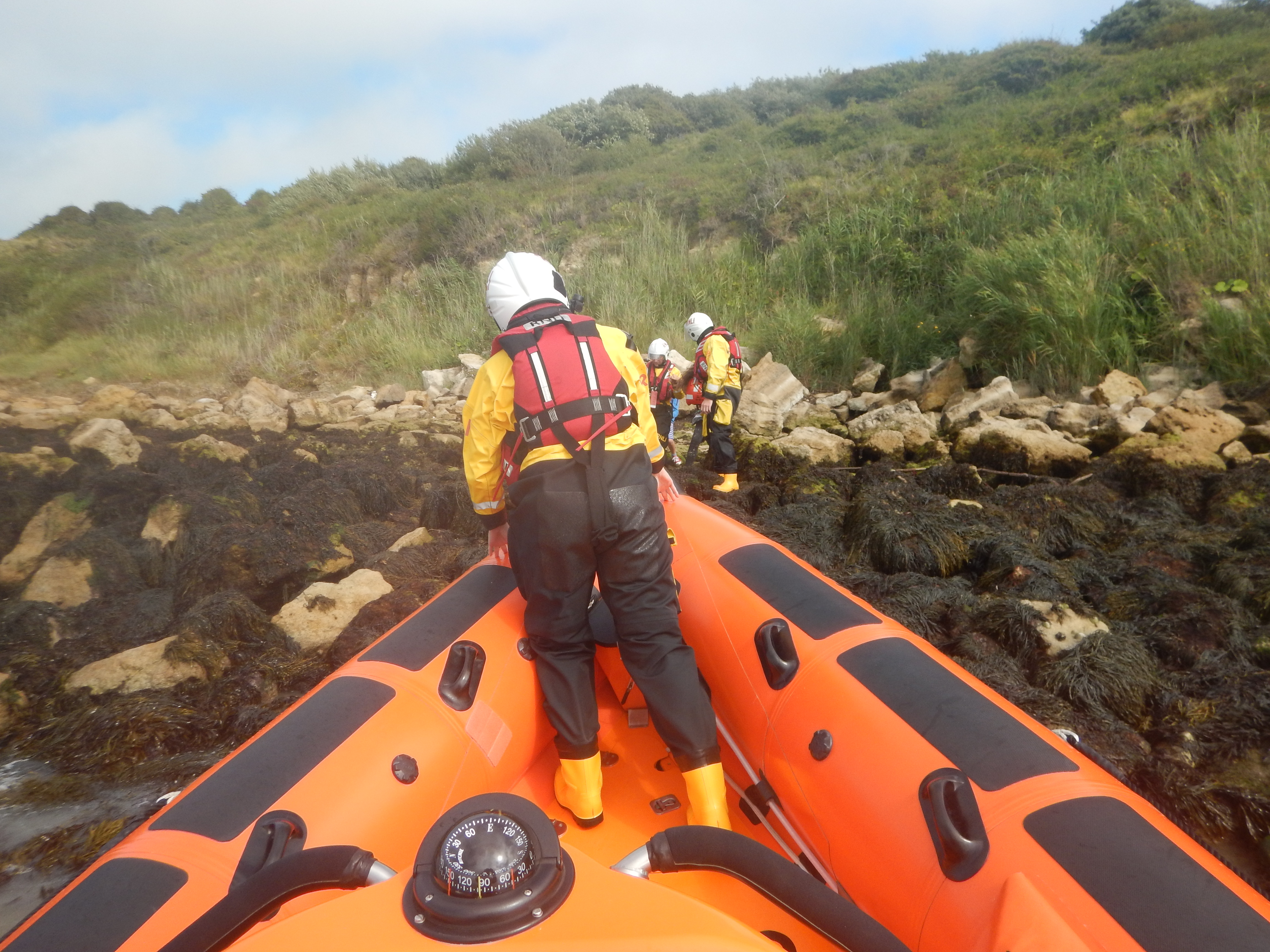 lifeboat members on the rocks with the mother and children