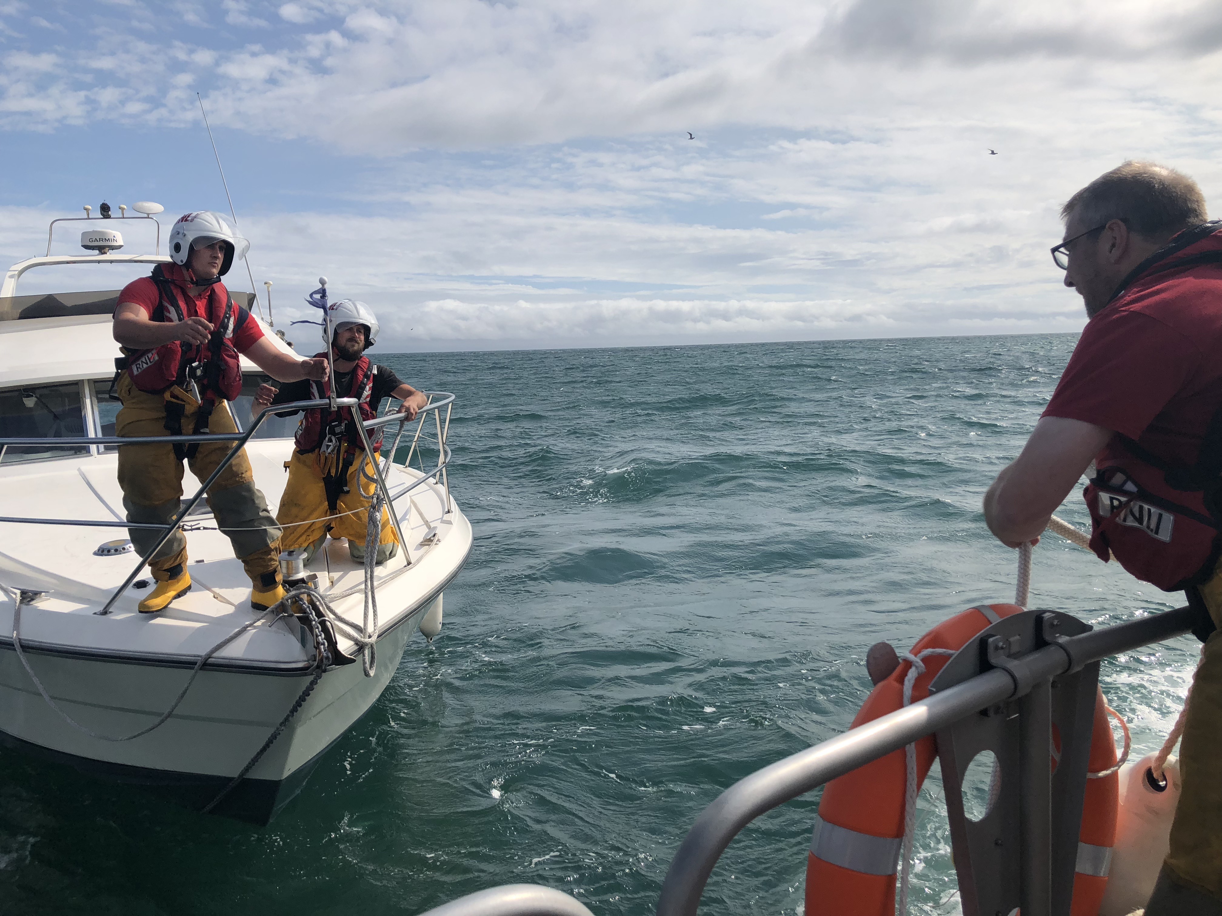 RNLI volunteers onboard casualty securing tow with lifeboat