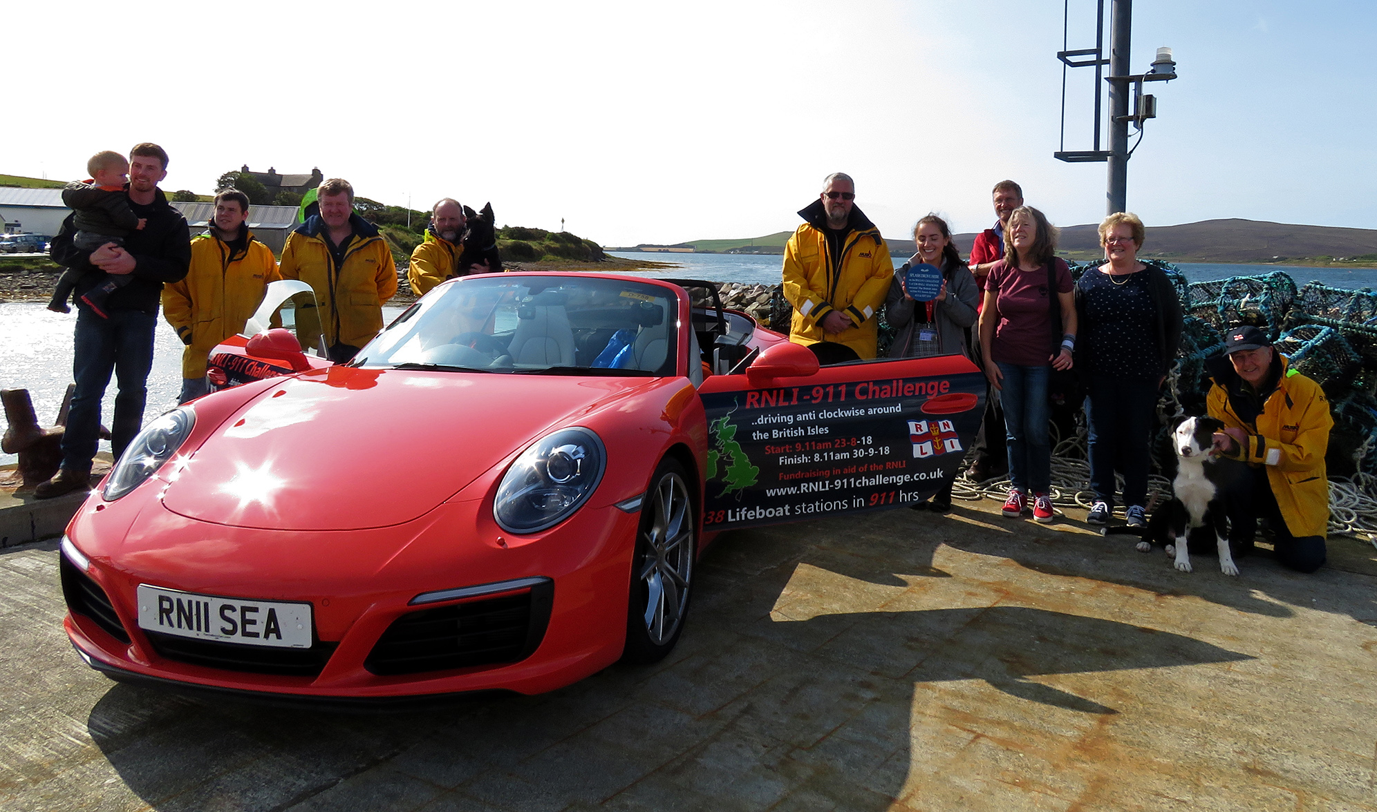 Porsche 911 on pier with members of RNLI Longhope