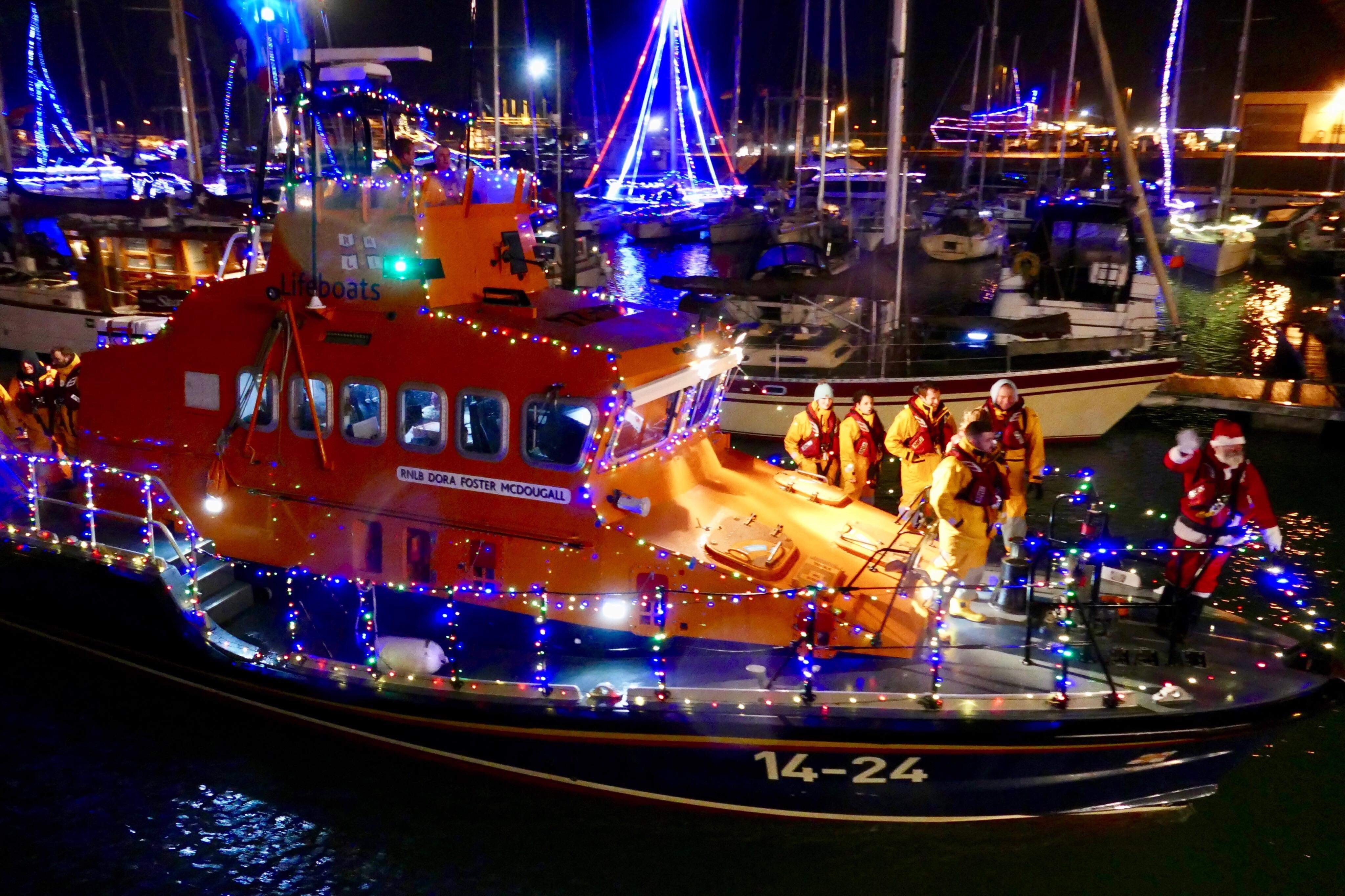The lifeboat touring the harbour with the yachts lit up in the background.