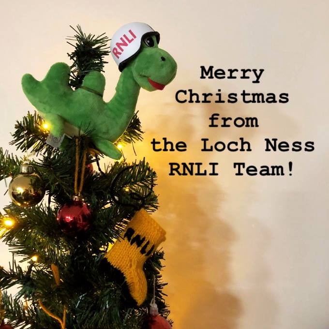 A Nessie toy on top of a Christmas tree, wearing an RNLI helmet