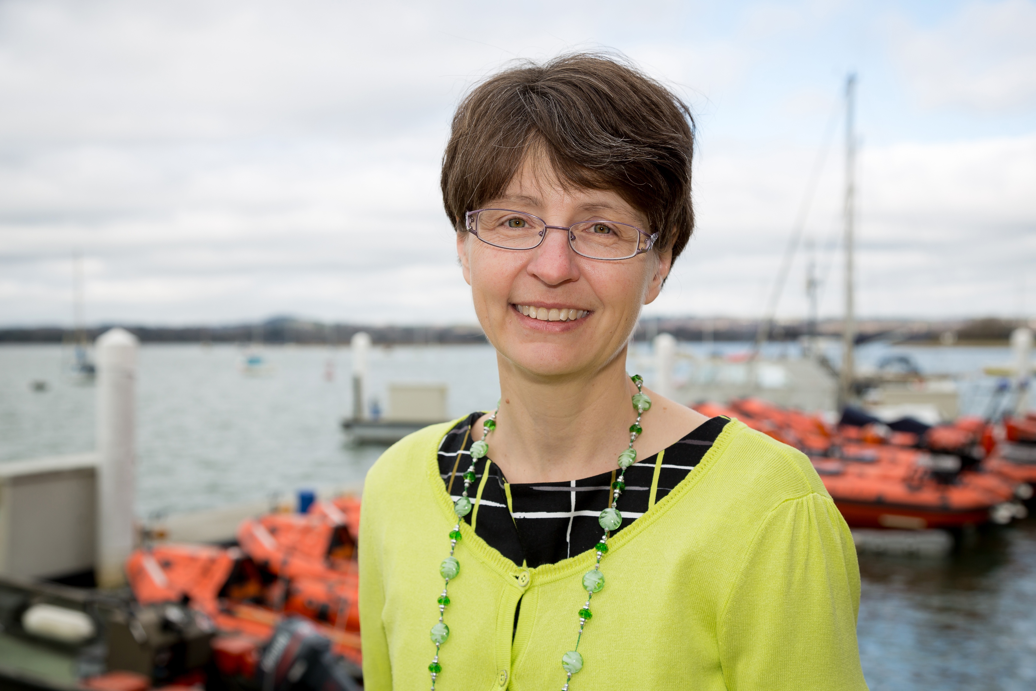Anjie Rook smiling at the camera with inshore lifeboats in the background