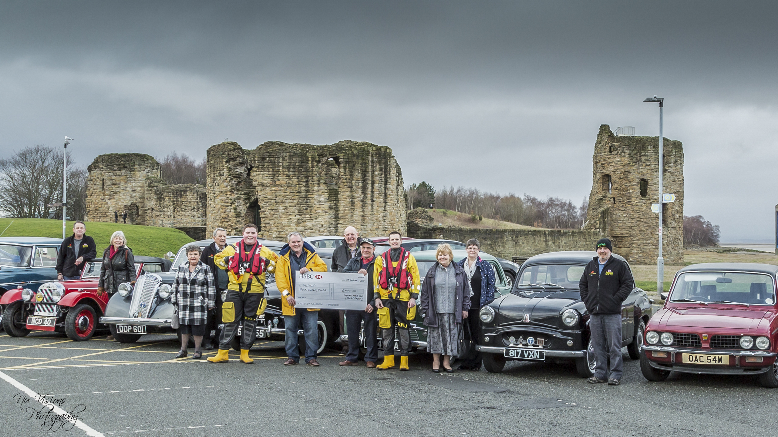 Members of the North Wales and Cheshire Standard Motor Club their vehicles, and RNLI volunteers accepting a cheque for £400