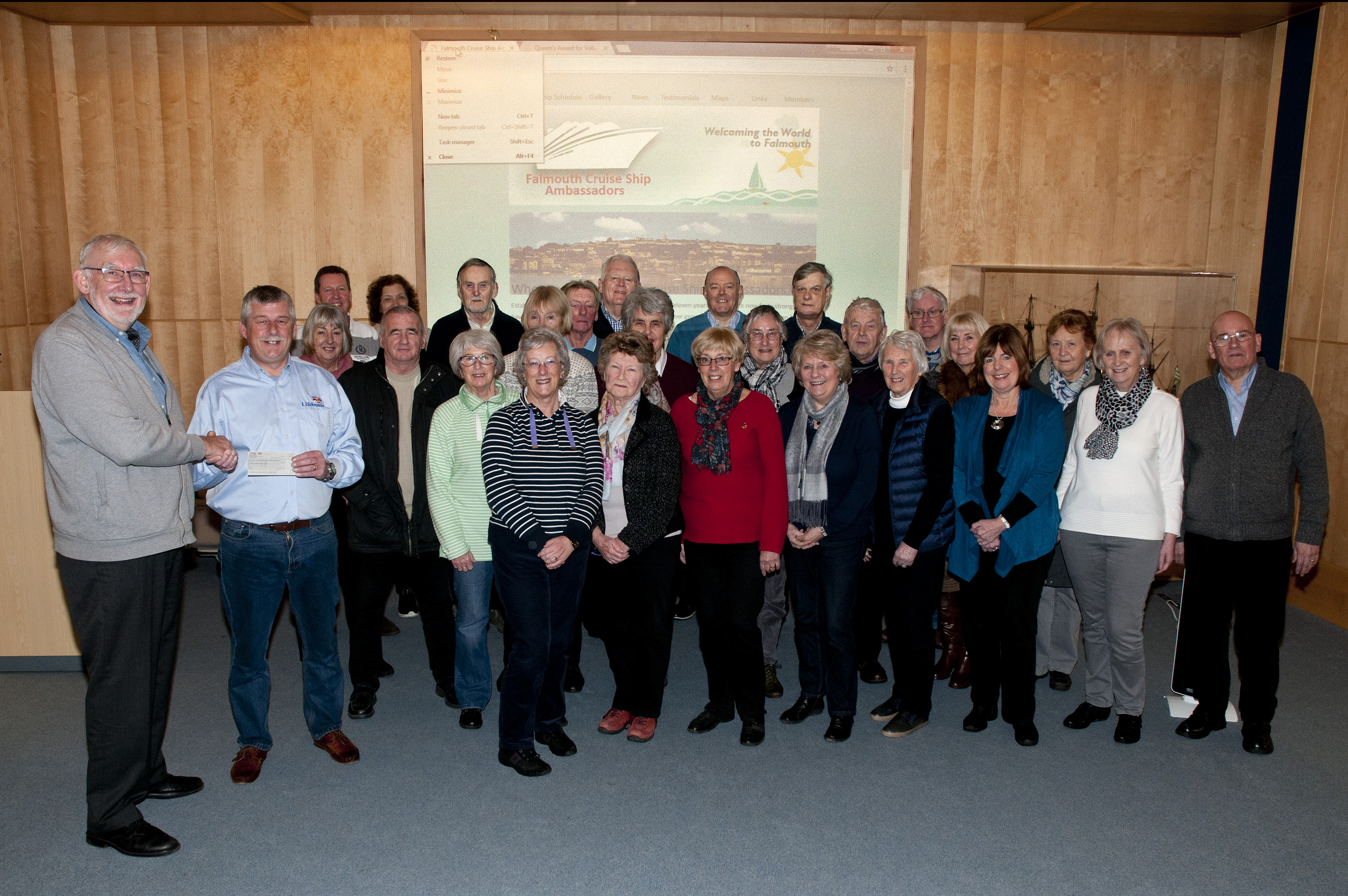 Keith Collins (left) presenting Falmouth Coxswain Jonathan Blakeston with the cheque at the National Maritime Museum Cornwall with members of the Falmouth Cruise Ship Ambassadors.