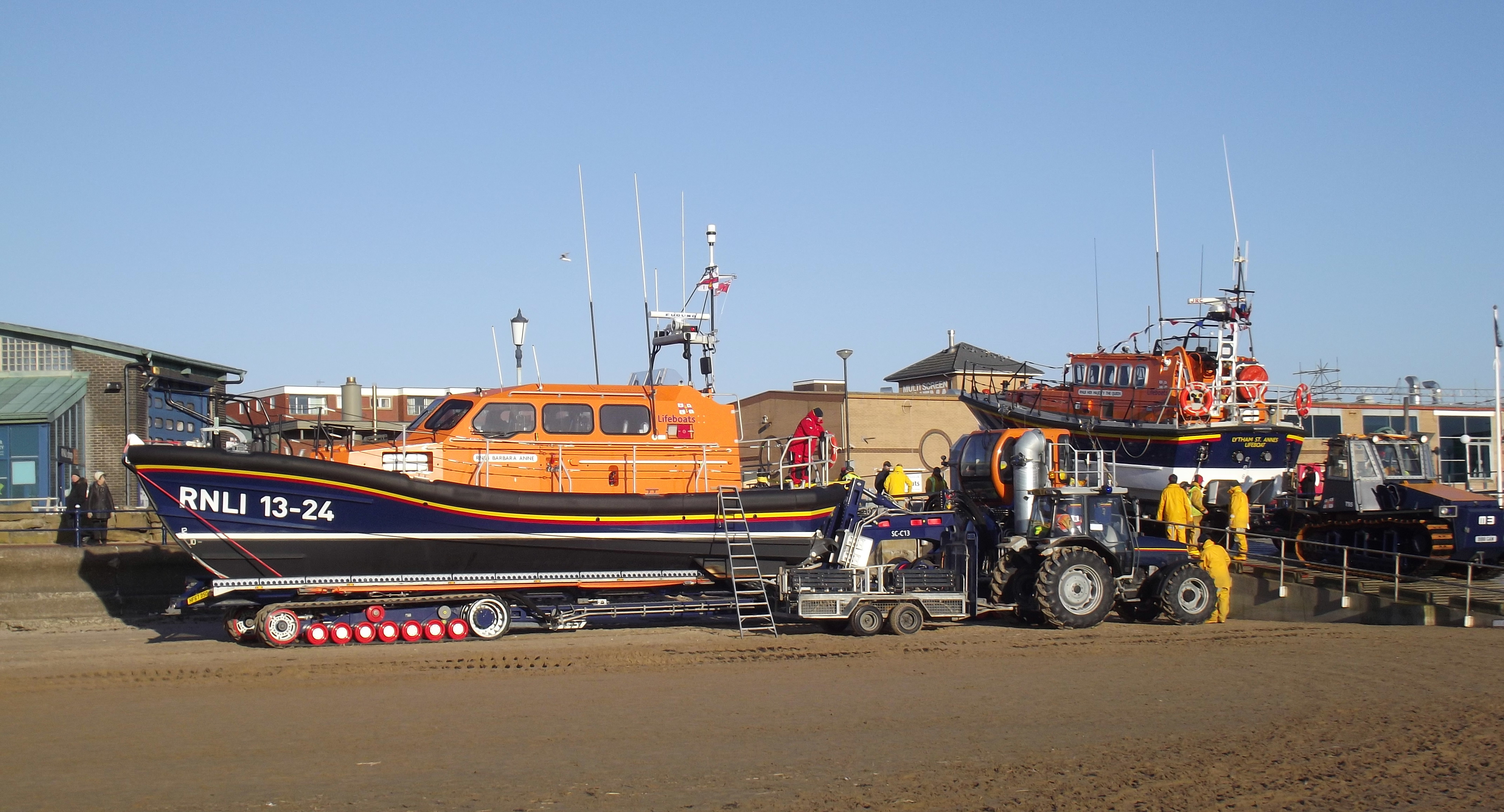 two lifeboats sit in front of a boathouse