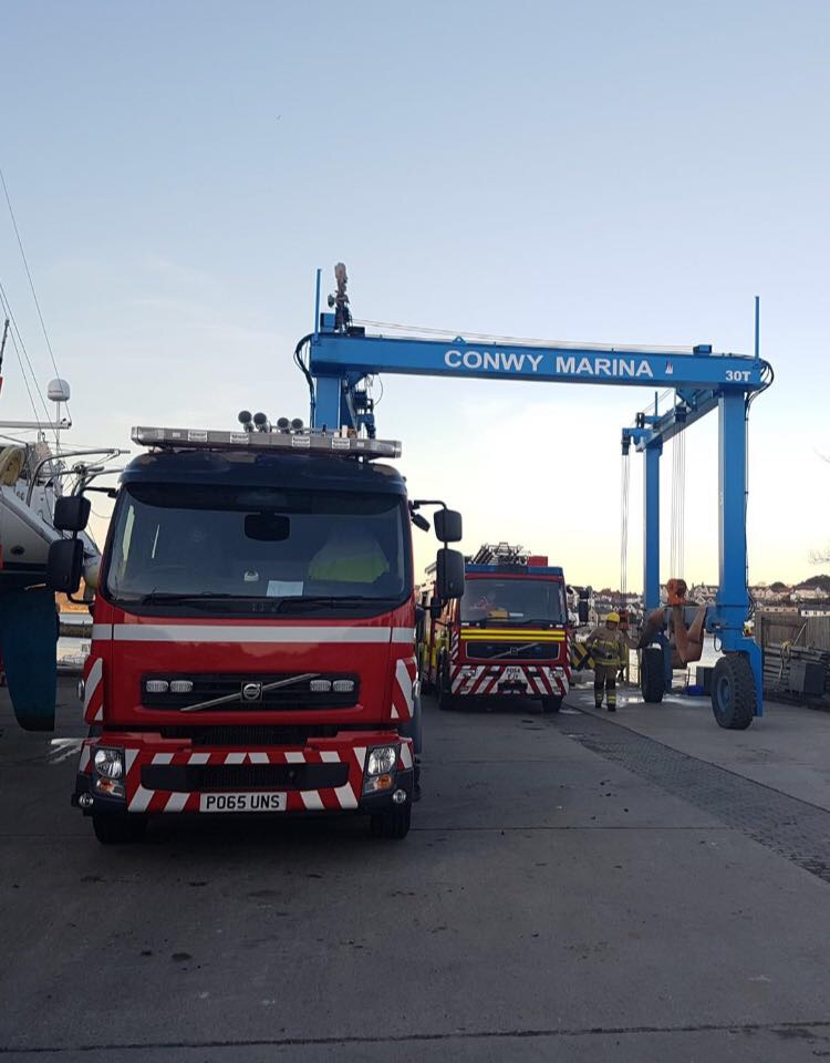 Two Fire Service appliances at the boatyard of Conwy Marina. Conwy Marina boat lift in the backdrop.