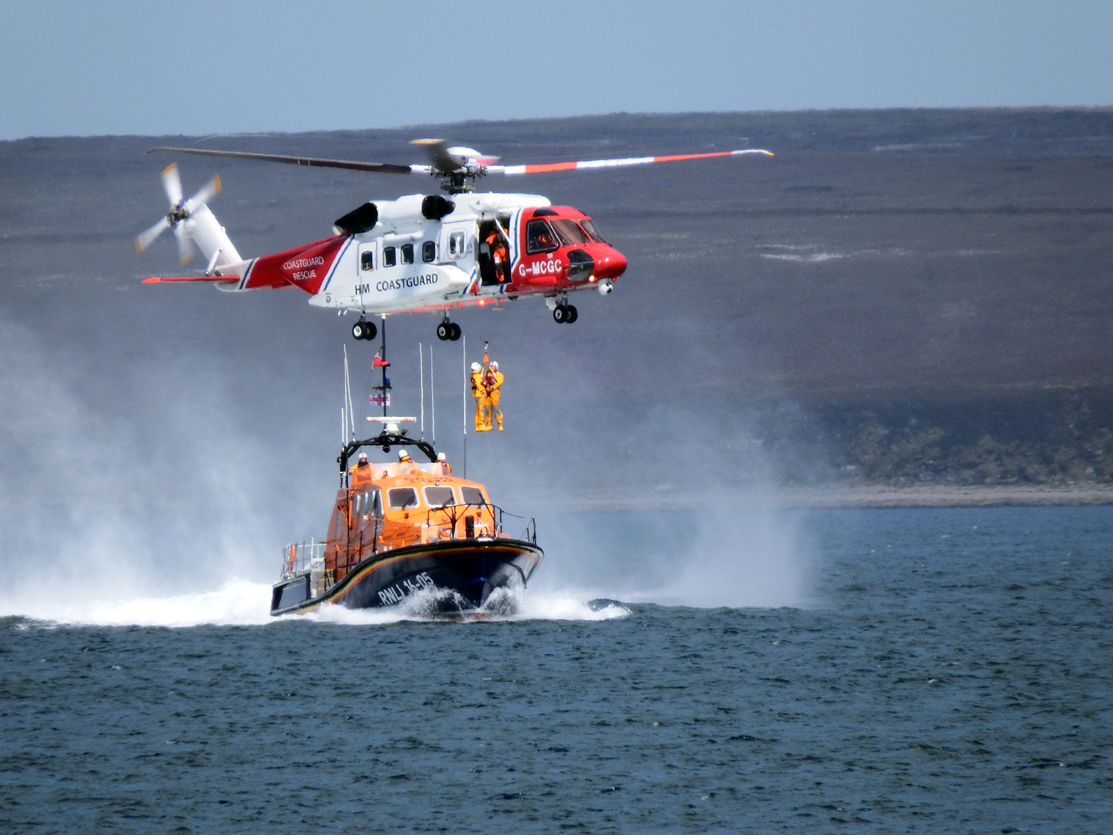Two crew members being winched into helicopter