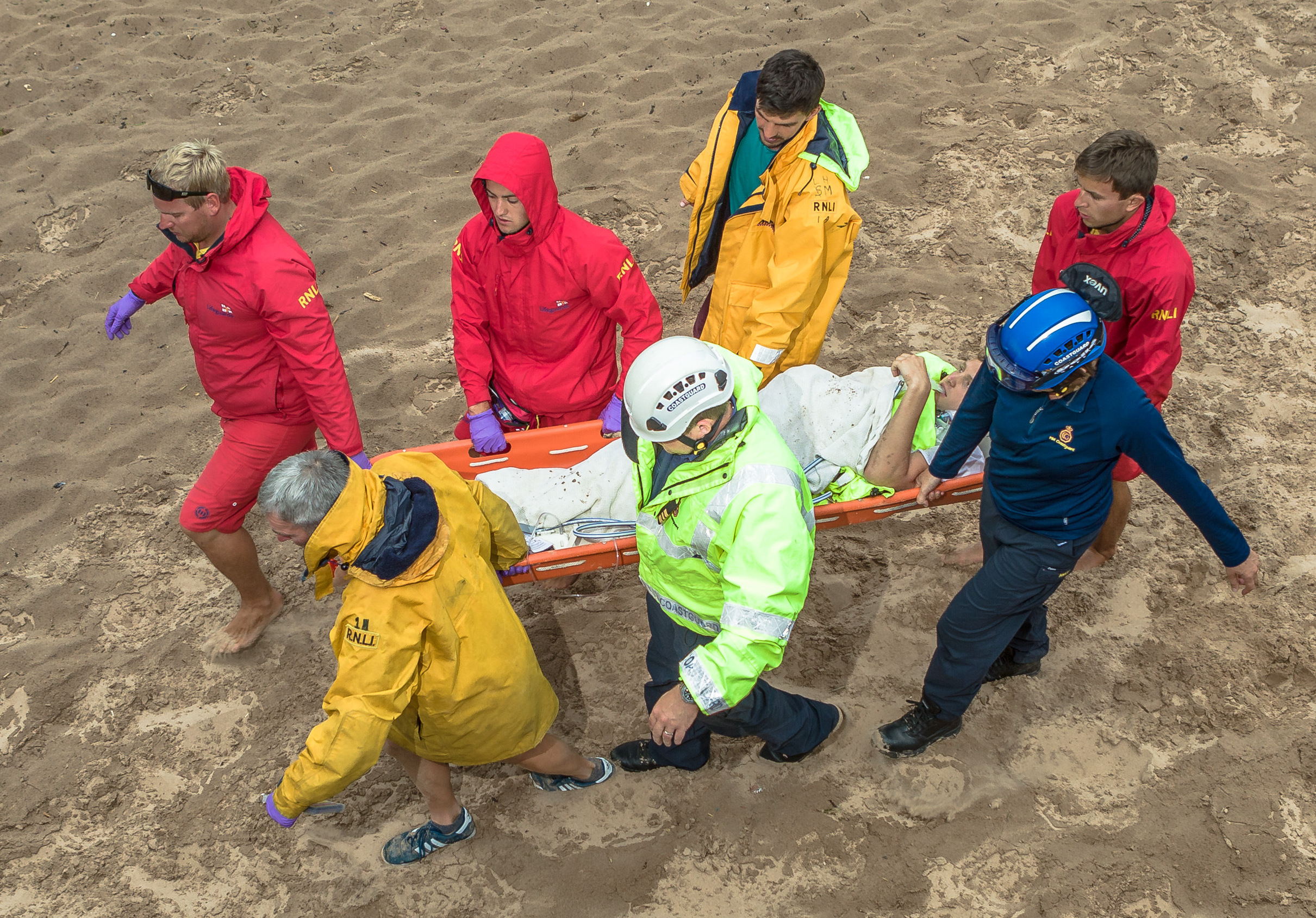 Exmouth lifeboat crew, RNLI lifeguards and Exmouth coastguards carry a cliff faller on a stretcher