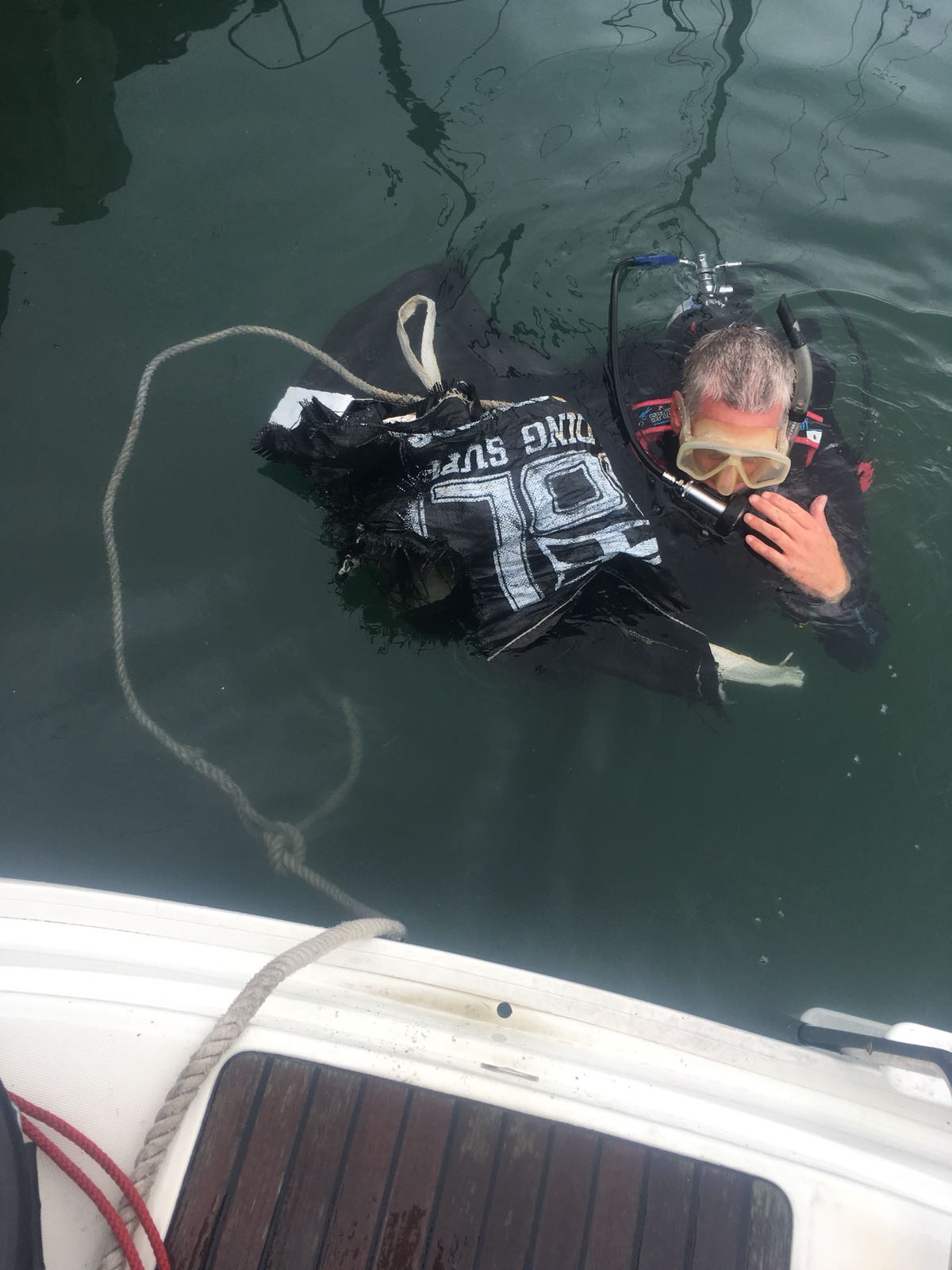 Yacht crew member removing debris from propellor