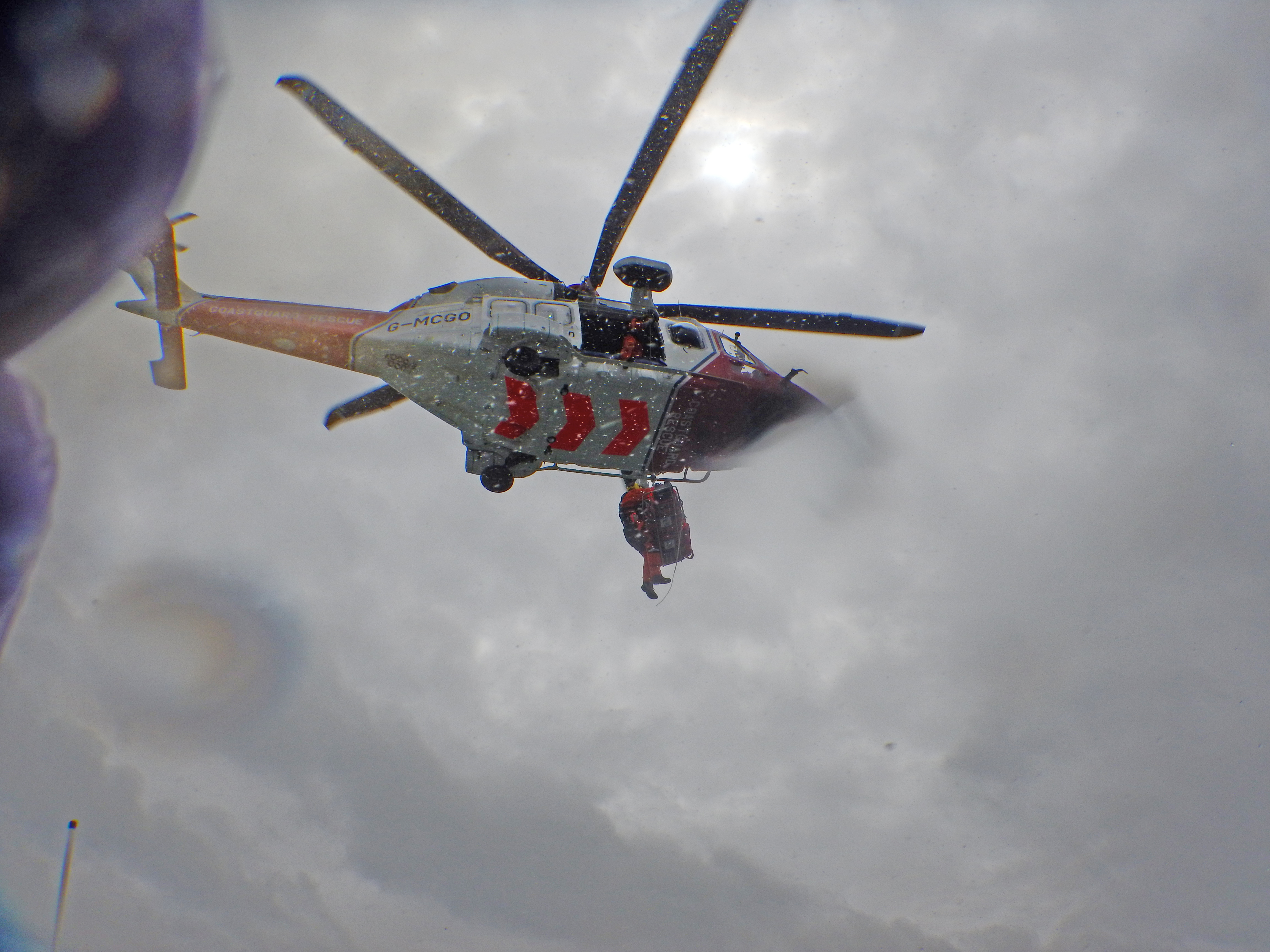 Stretchered man arrives near the door of the helicopter.