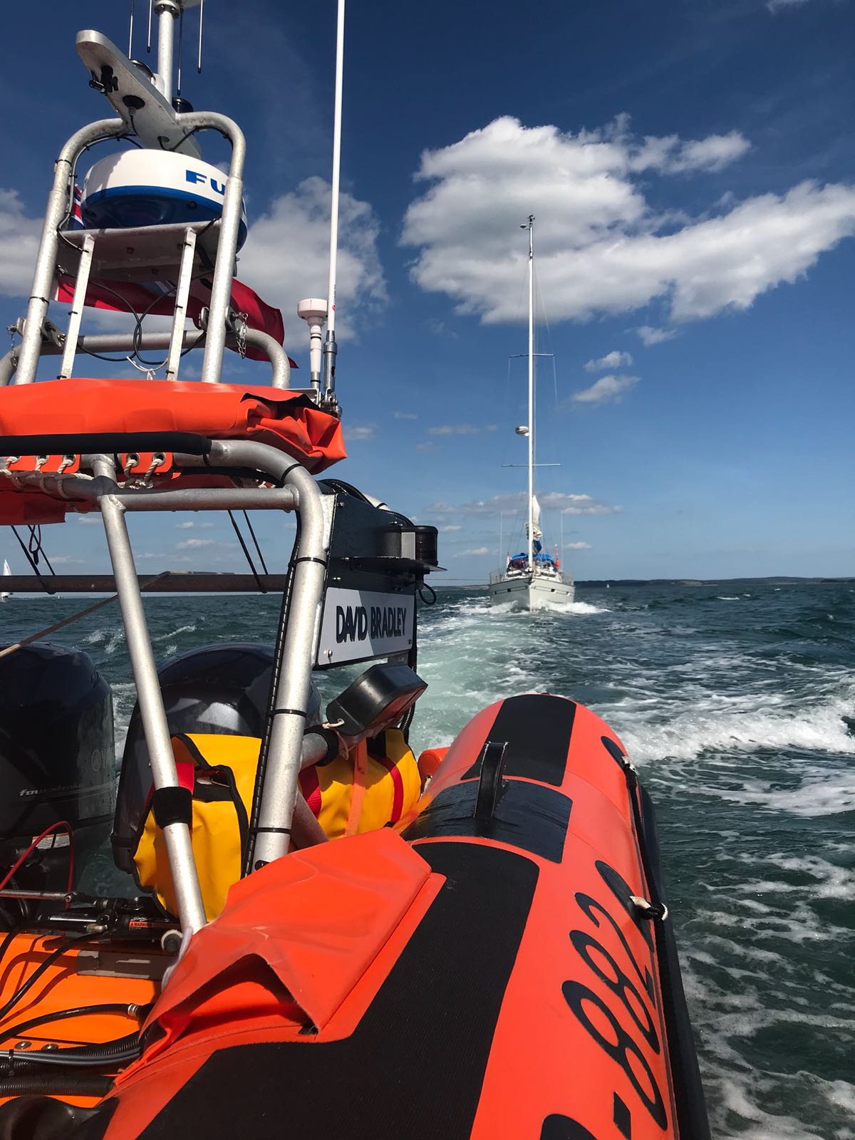 Looking astern at Lymington RNLI lifeboat with yacht in tow